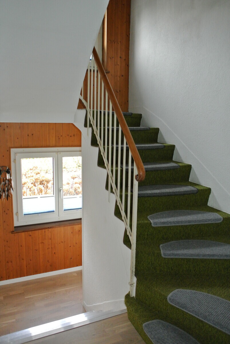 Treppenhaus mit grünem Teppich und Holzverkleidung
