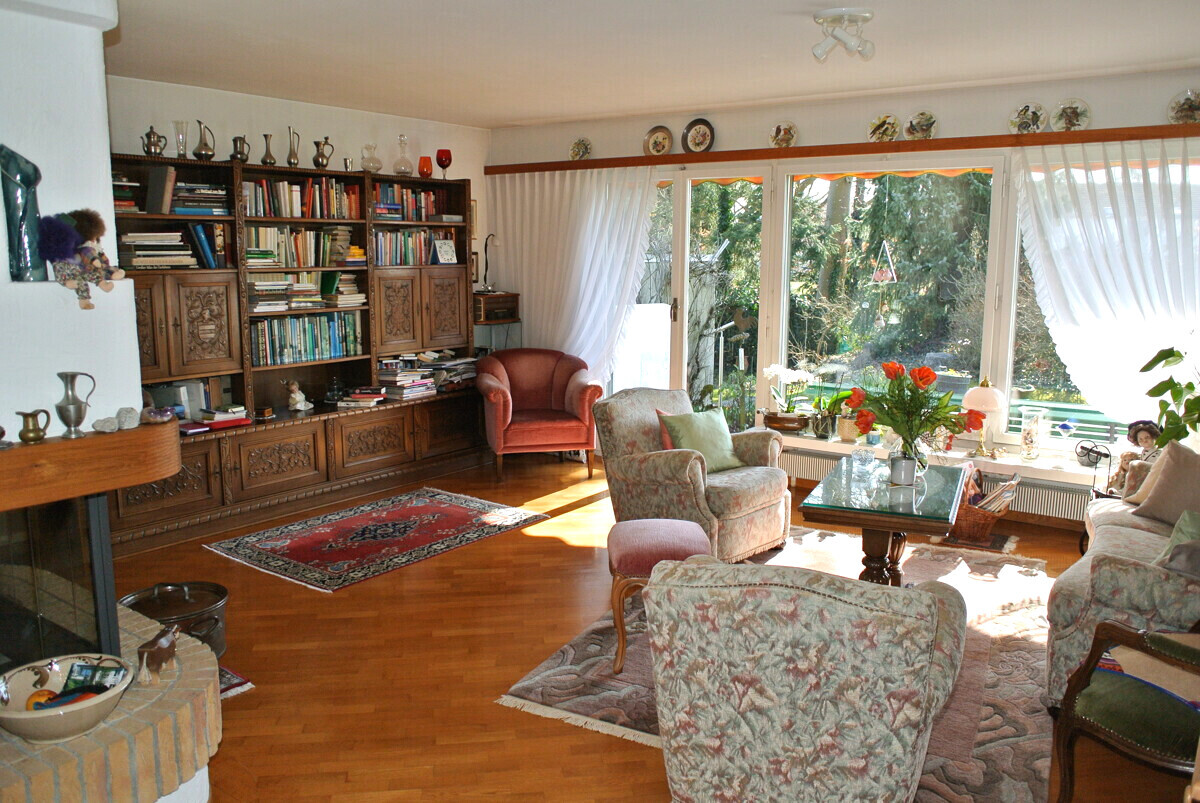 Gemütliches Wohnzimmer mit großem Bücherregal und Gartenblick
