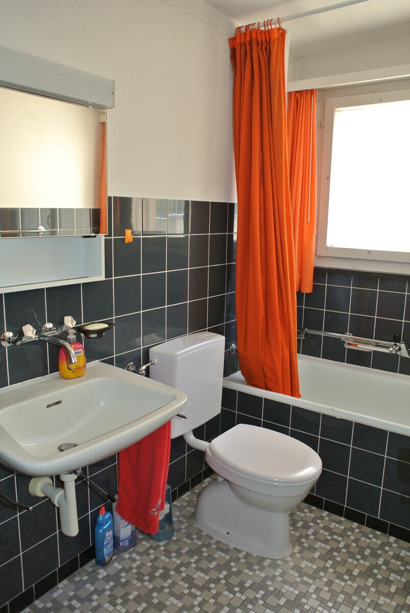 Kleines Badezimmer mit orangefarbenem Vorhang