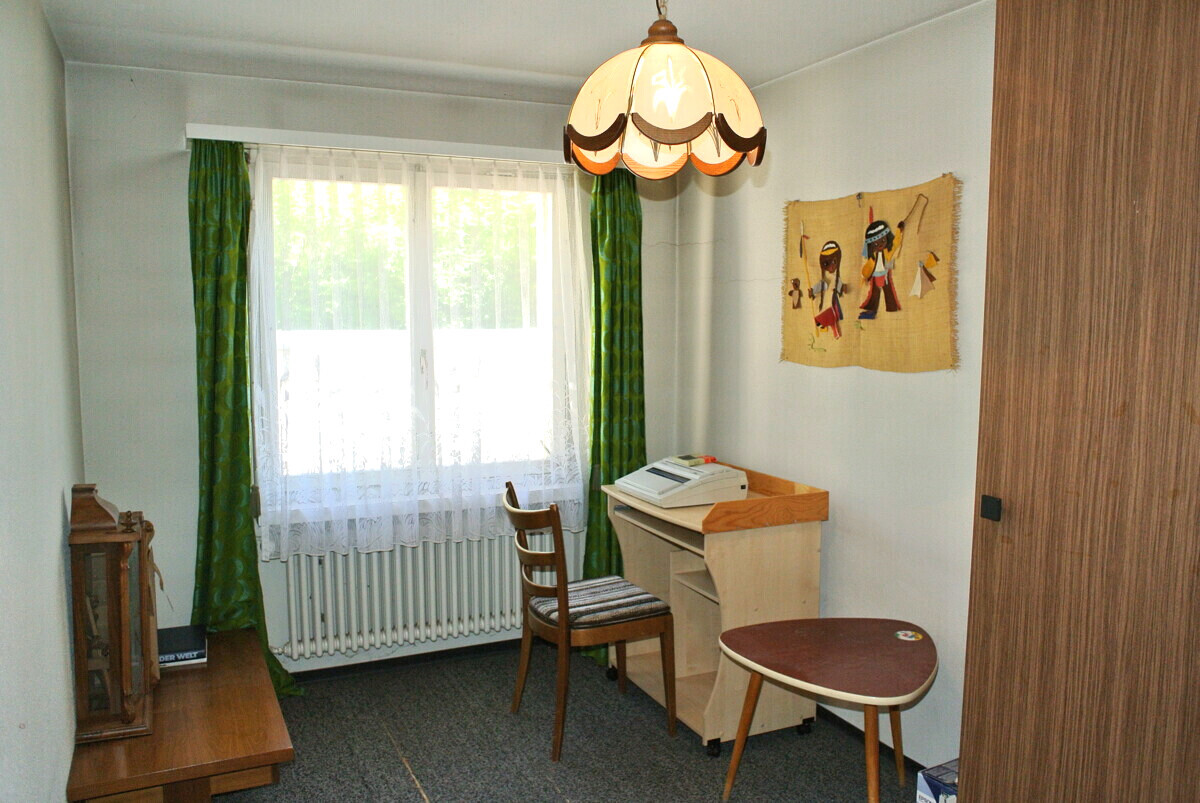 Kleines Zimmer mit Fenster und einfacher Einrichtung