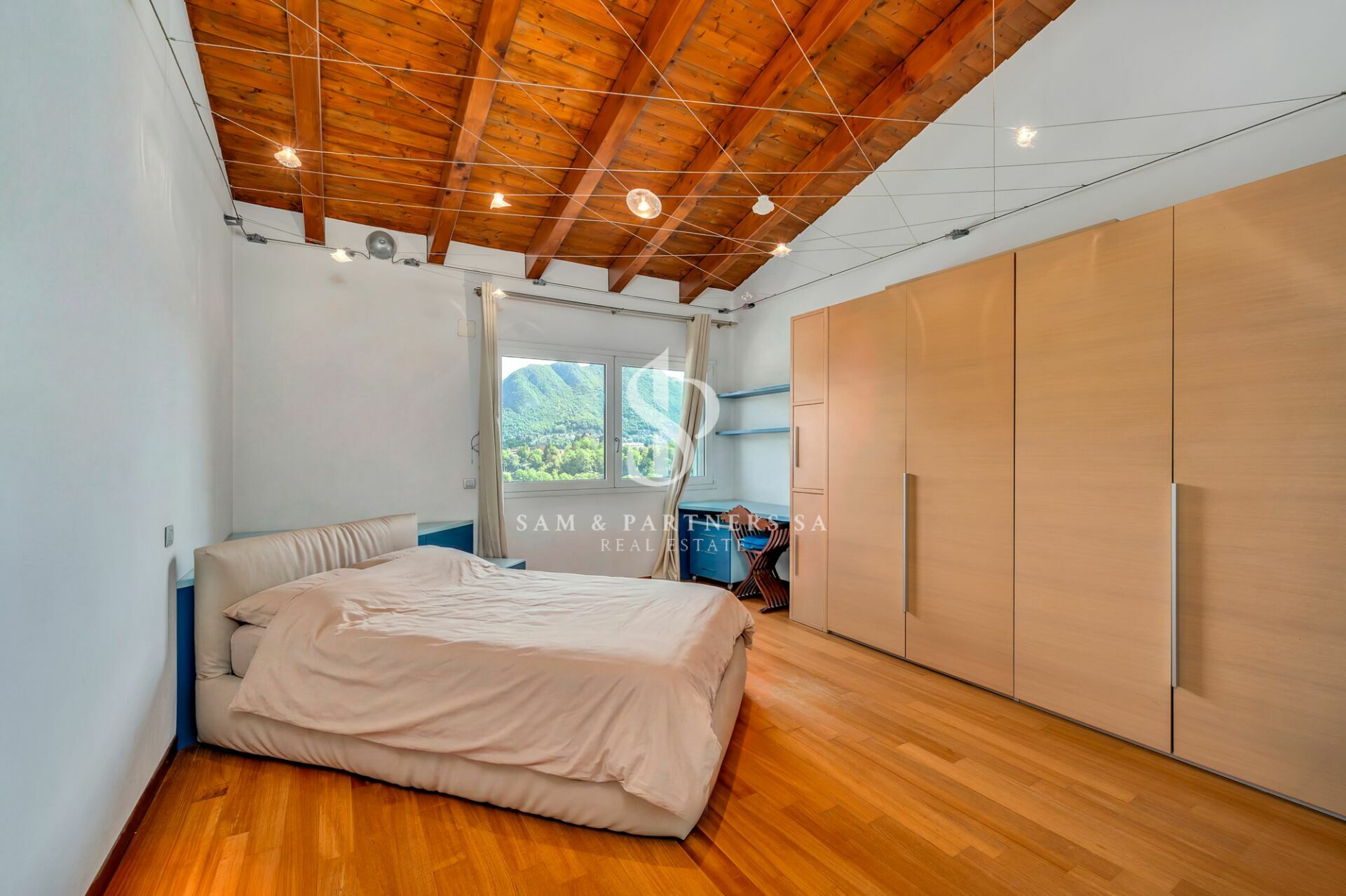 Helles Schlafzimmer mit Holzbalkendecke und Bergblick
