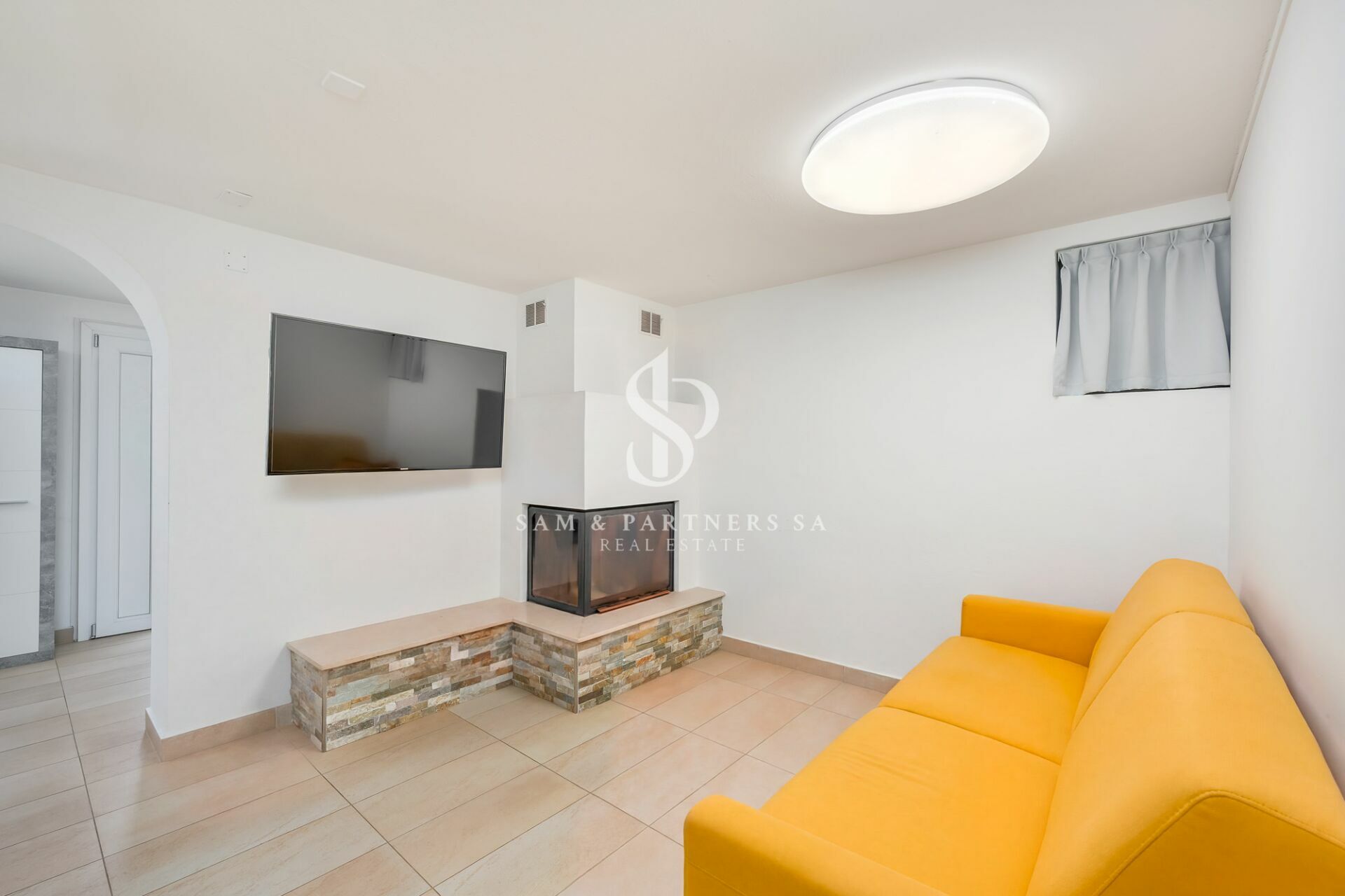 Heller Wohnraum mit Kamin und gelbem Sofa