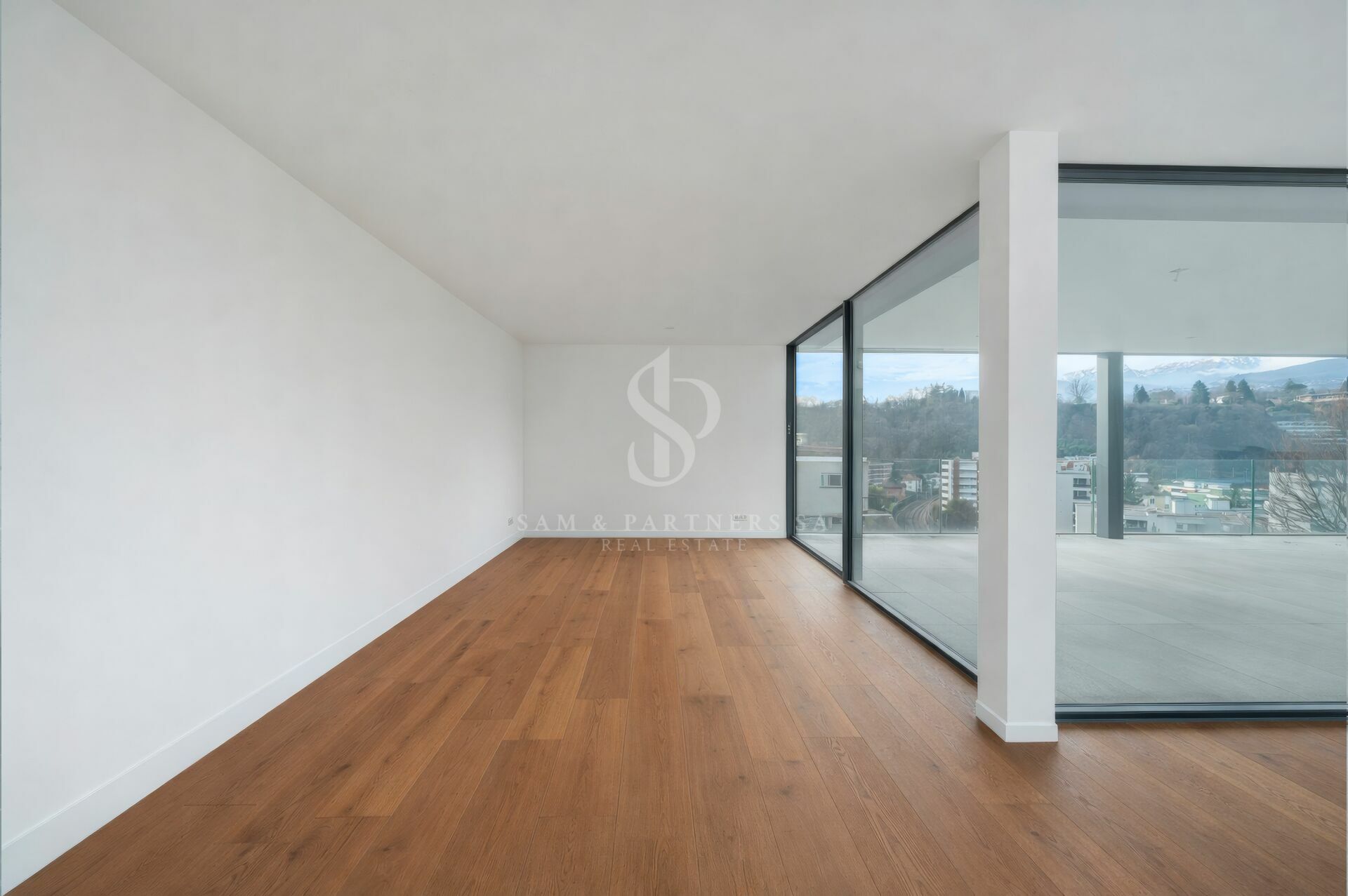Heller leerer Wohnraum mit Holzparkett und großer Glasfront