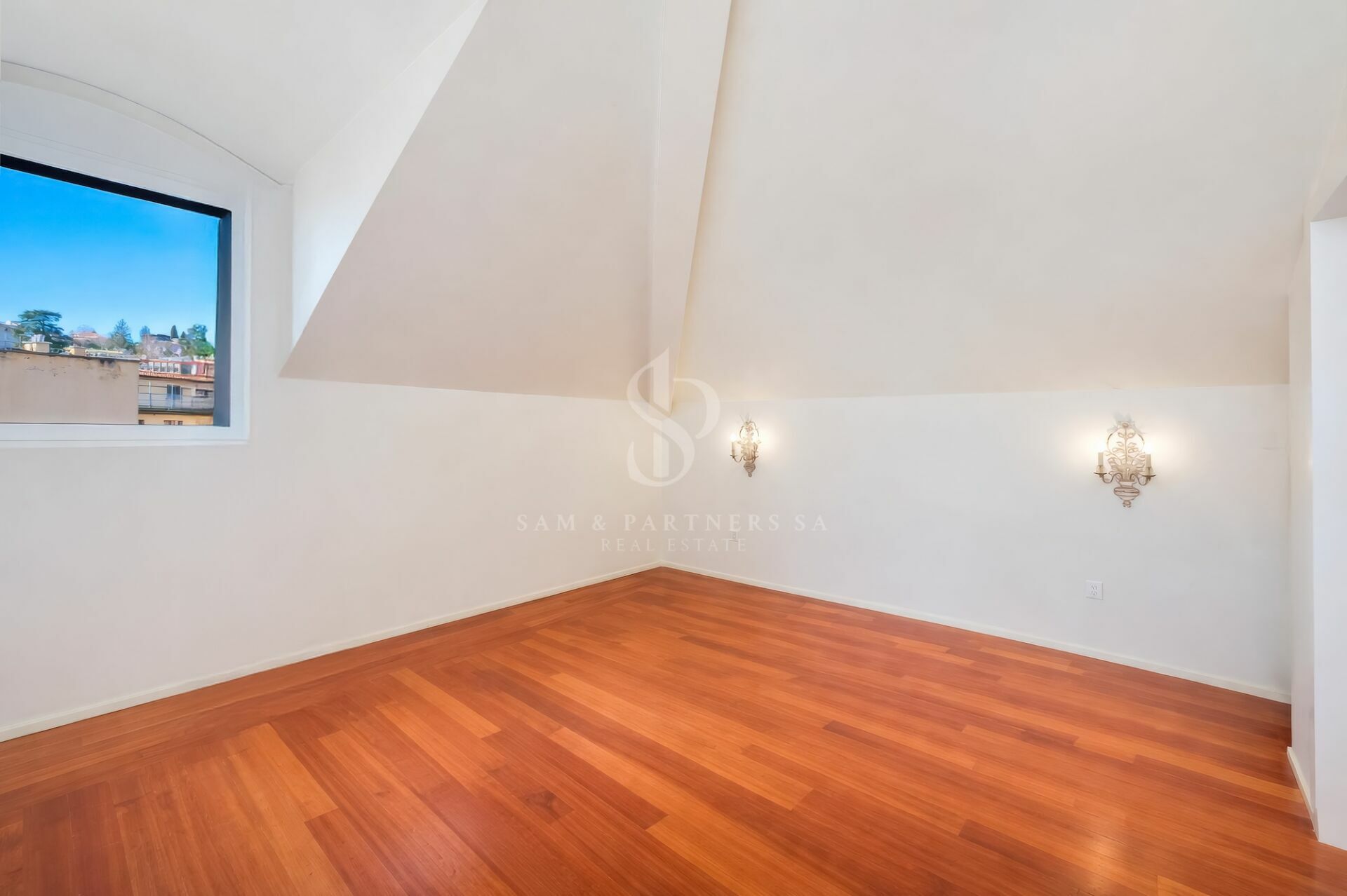 Heller leerer Raum mit Dachschrägen und Holzfußboden