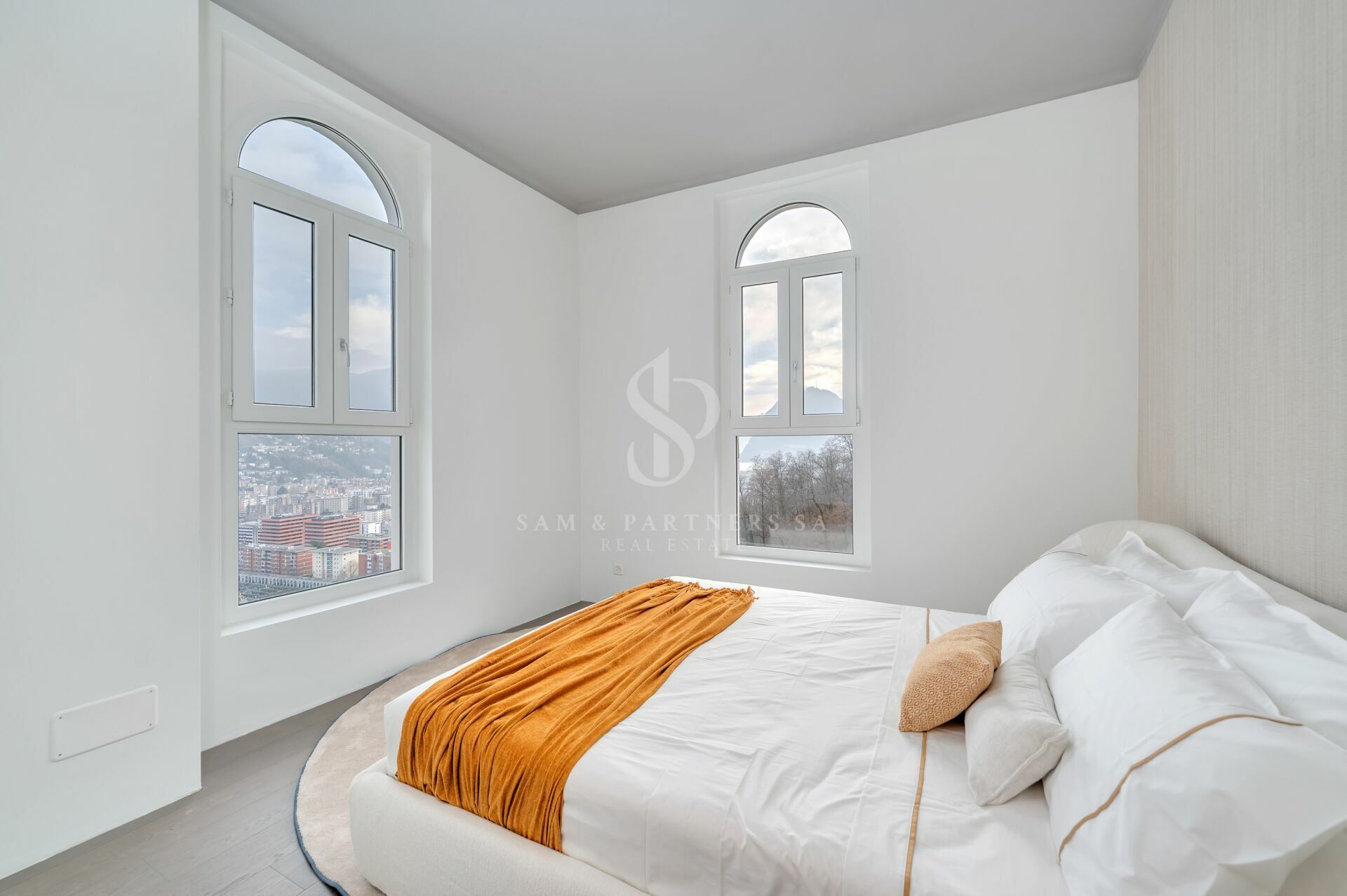 Helles Schlafzimmer mit Rundbogenfenstern und Stadtblick