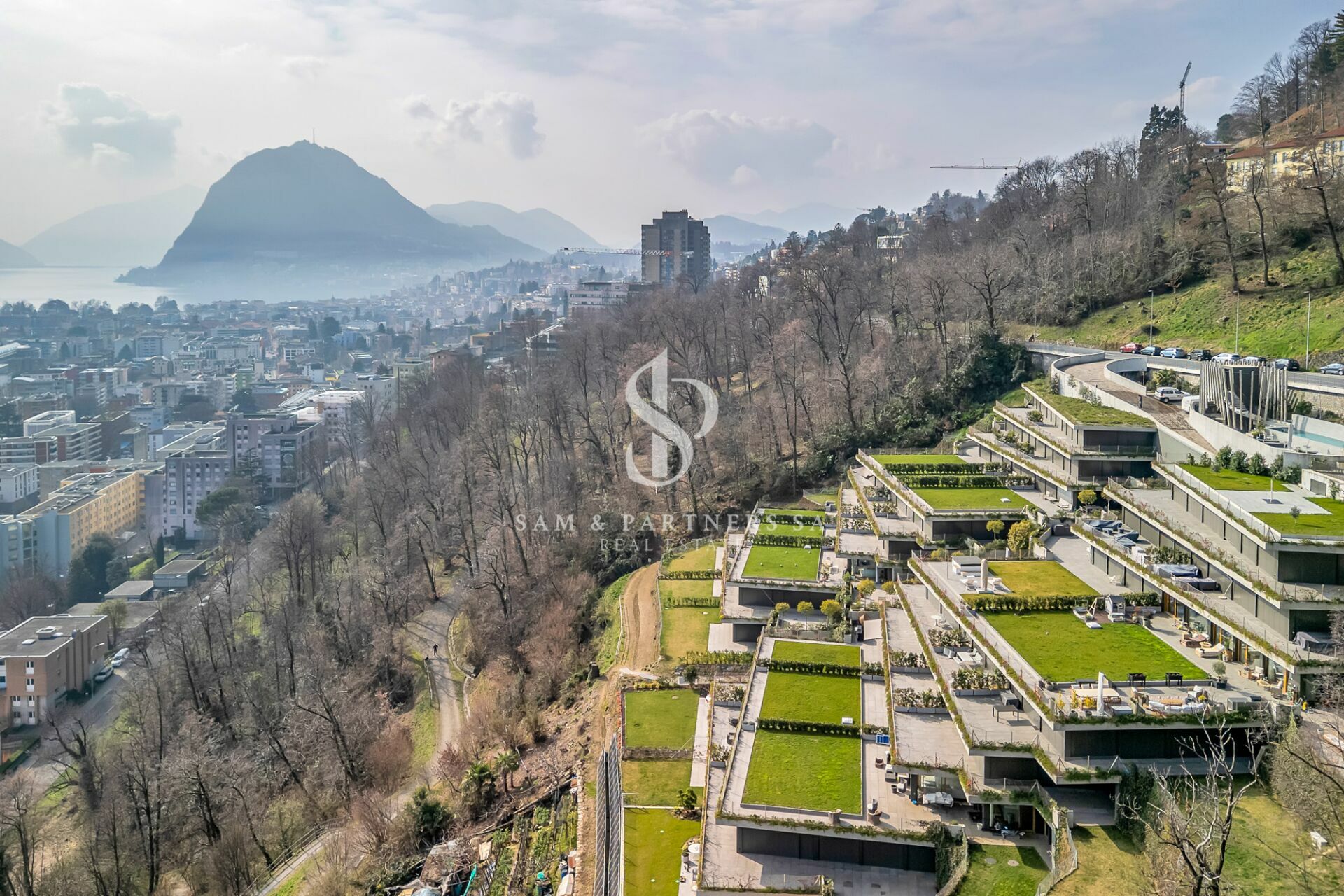 Panoramablick auf ein terrassiertes Hanggrundstück mit Stadt- und Seesicht