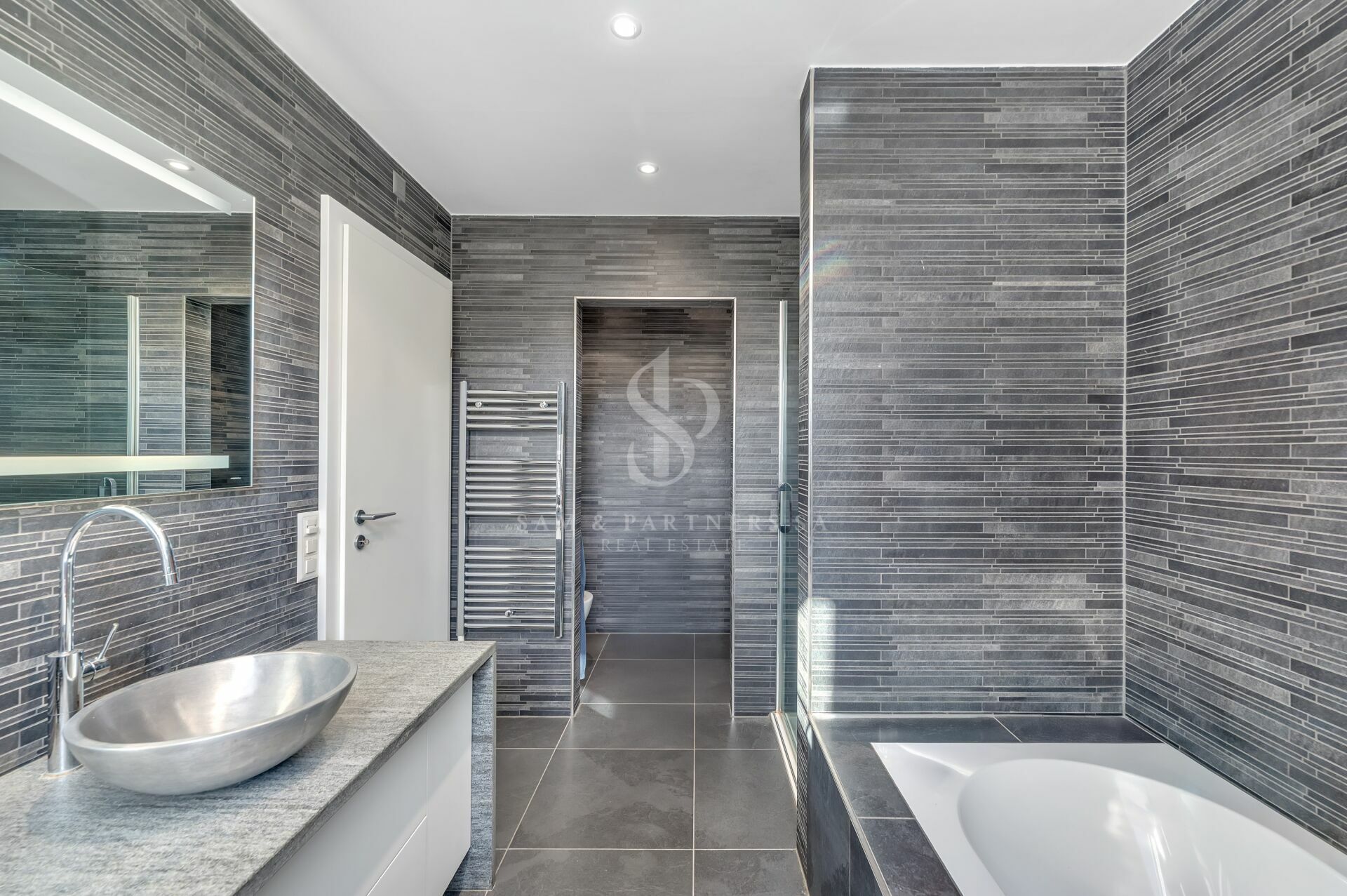 Modernes Badezimmer mit grauen Fliesen und Badewanne
