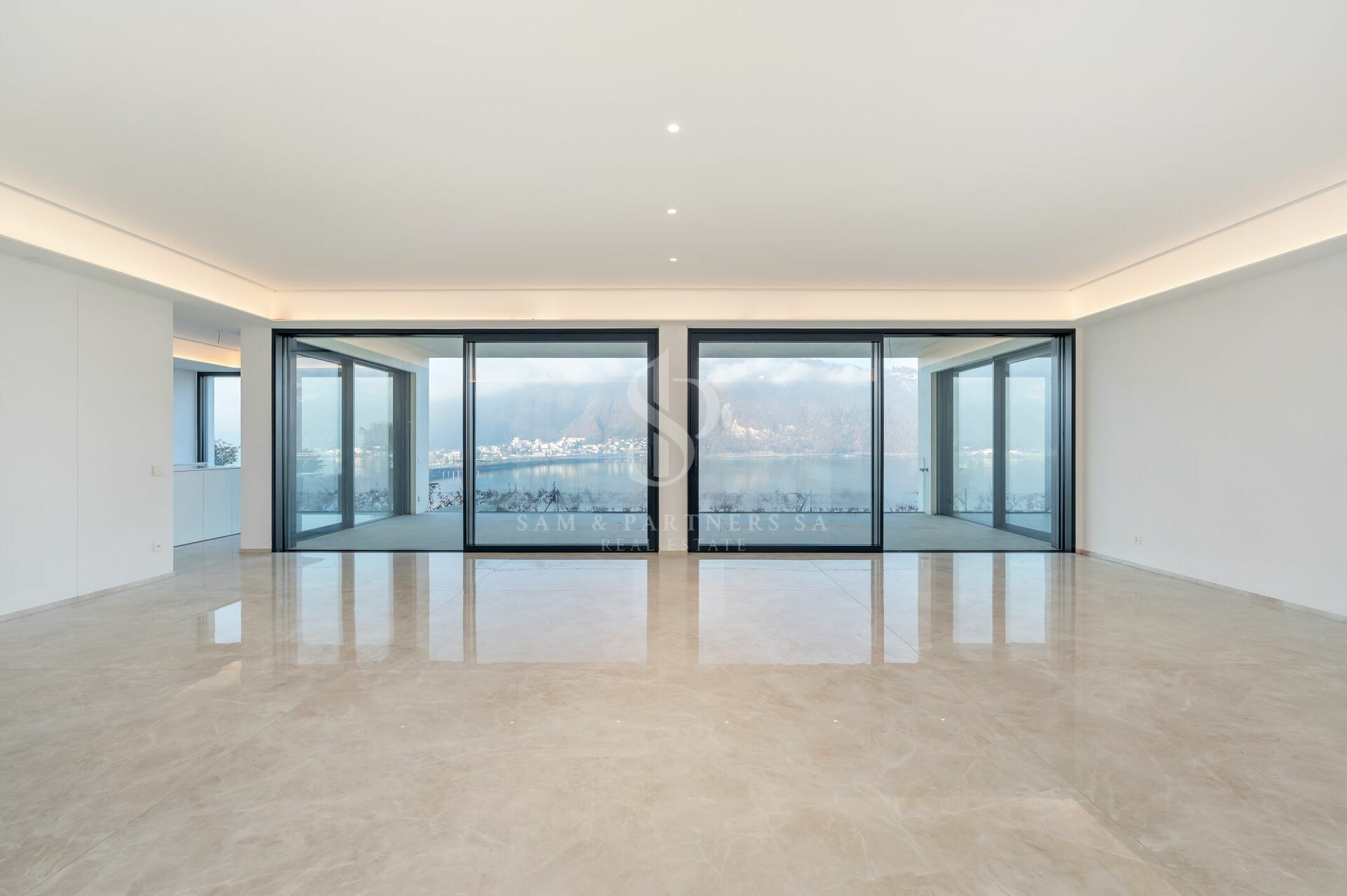 Großer leerer Wohnbereich mit Panoramafenstern und Seeblick