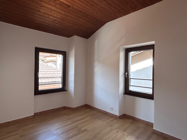 Leerer Raum mit Holzdecke und zwei Fenstern