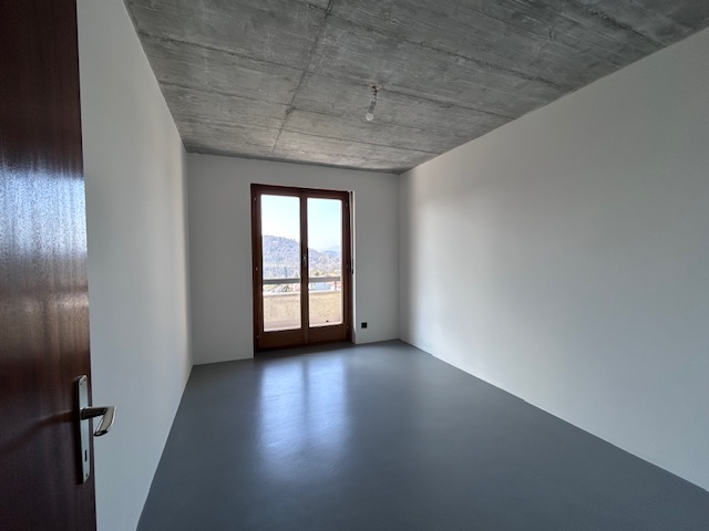 Leerer Raum mit Sichtbetondecke und Balkon-/Terrassentür