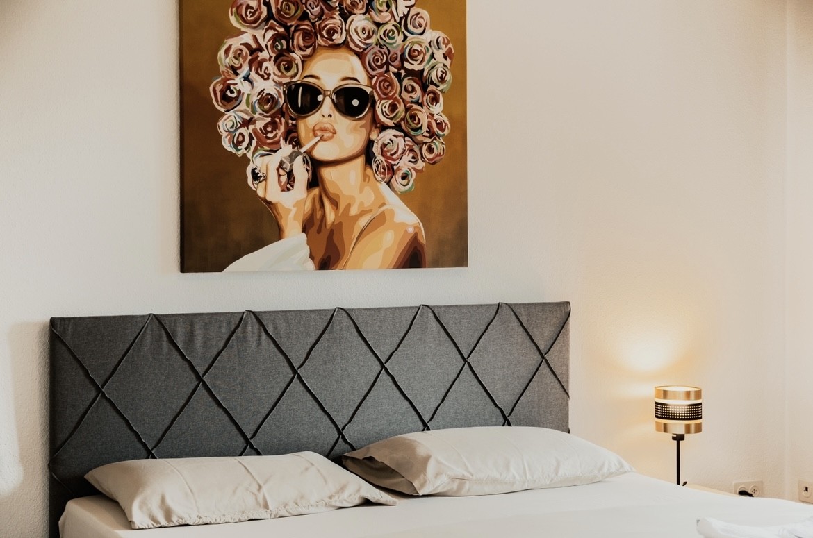 Schlafzimmer mit gepolstertem Kopfteil und Wandbild