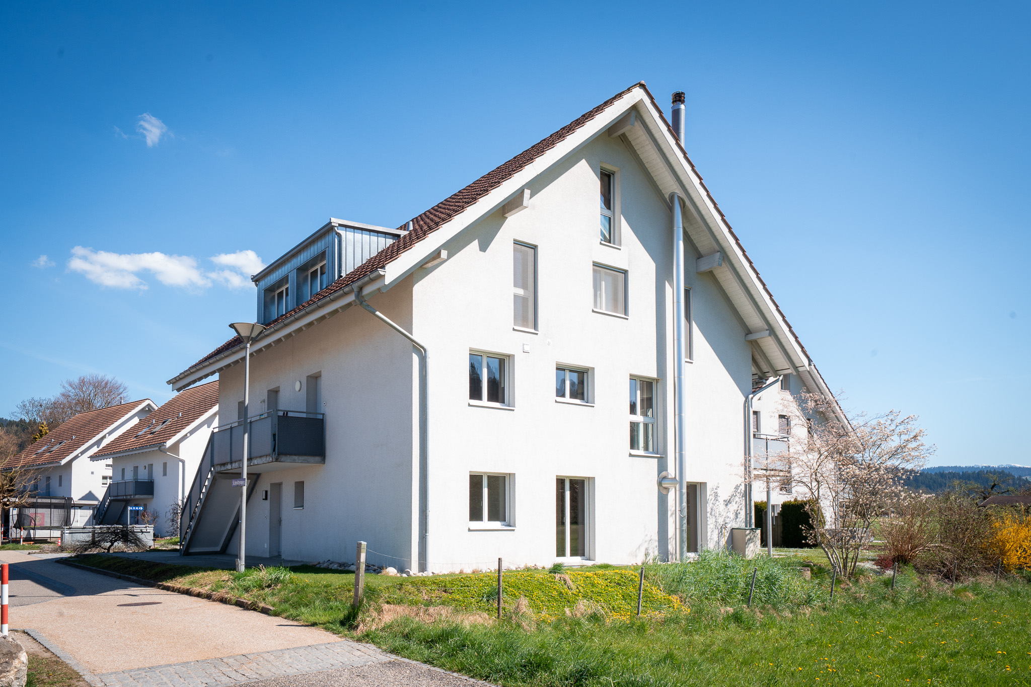 Mehrfamilienhaus mit Satteldach und weißer Putzfassade