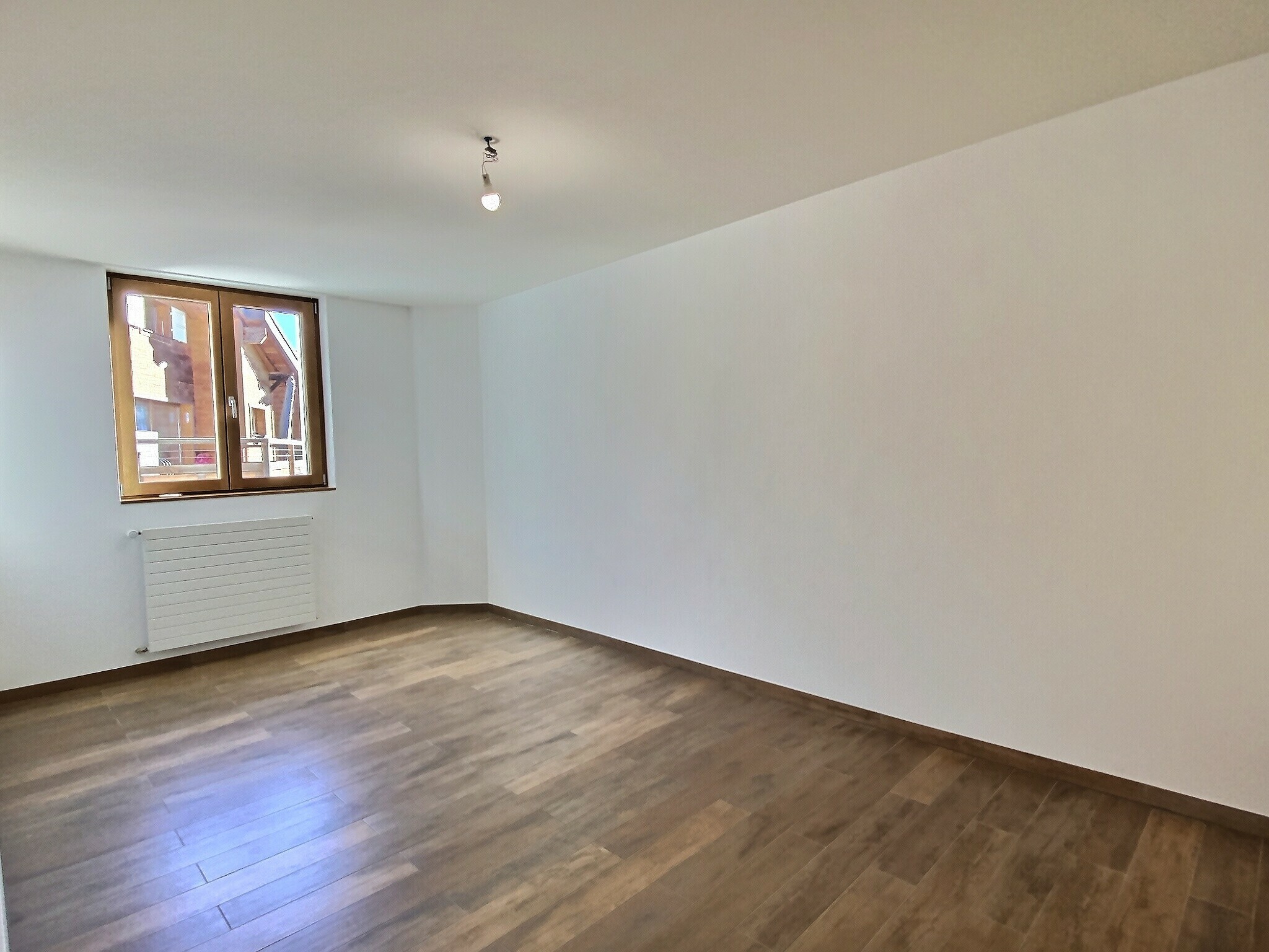 Leerer, renovierter Raum mit Holzfenster und Heizkörper