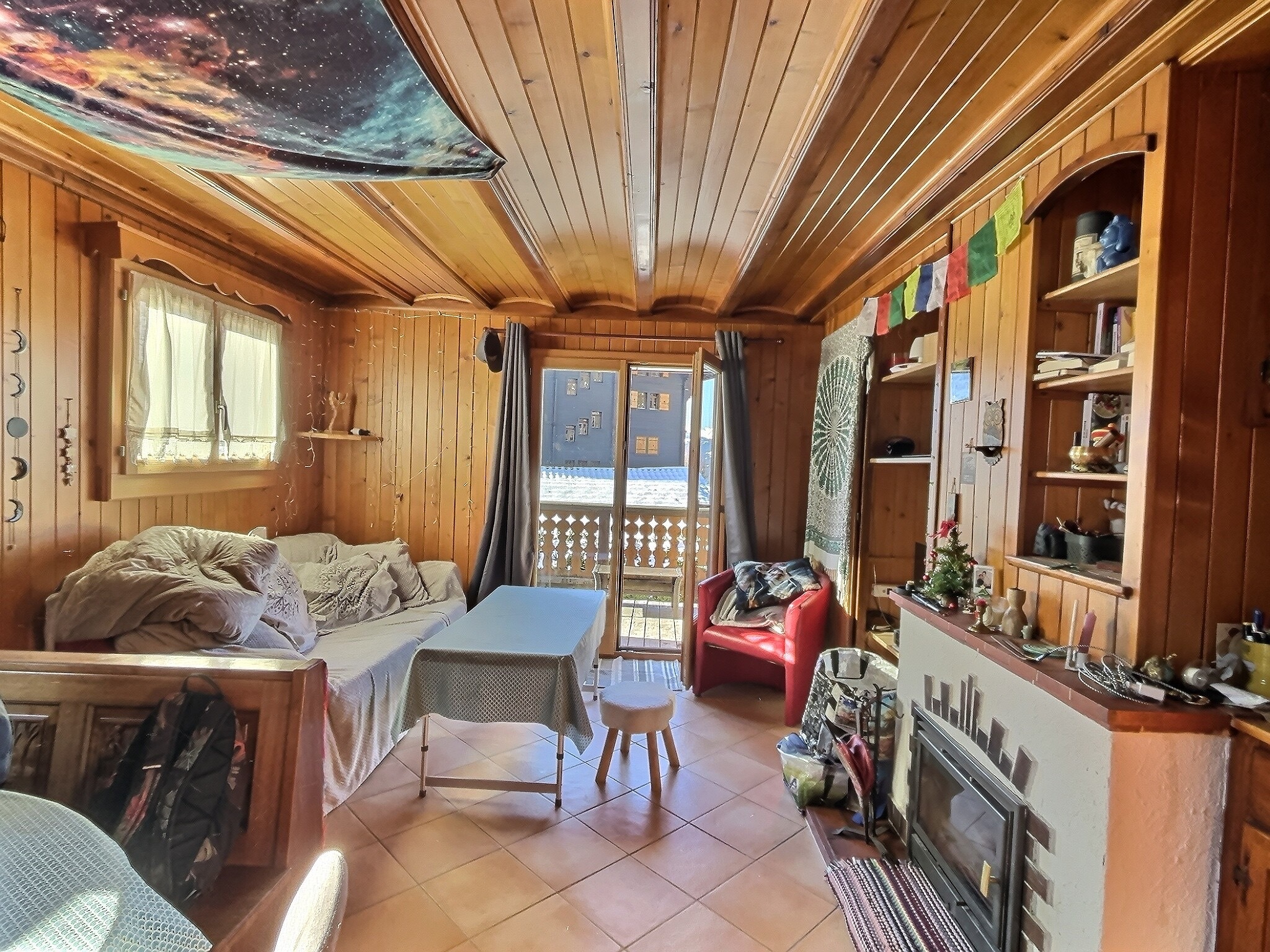 Gemütliches holzverkleidetes Wohnzimmer mit Balkonzugang