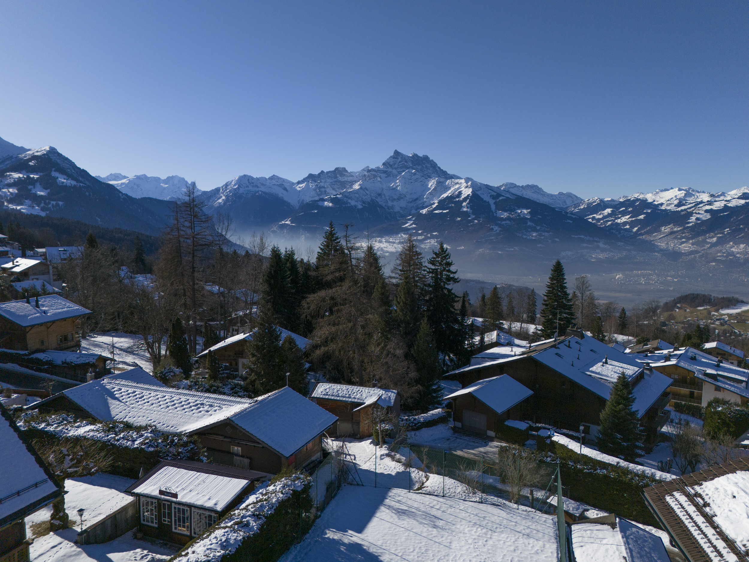 Schneebedecktes Bergpanorama über einer alpinen Wohnsiedlung
