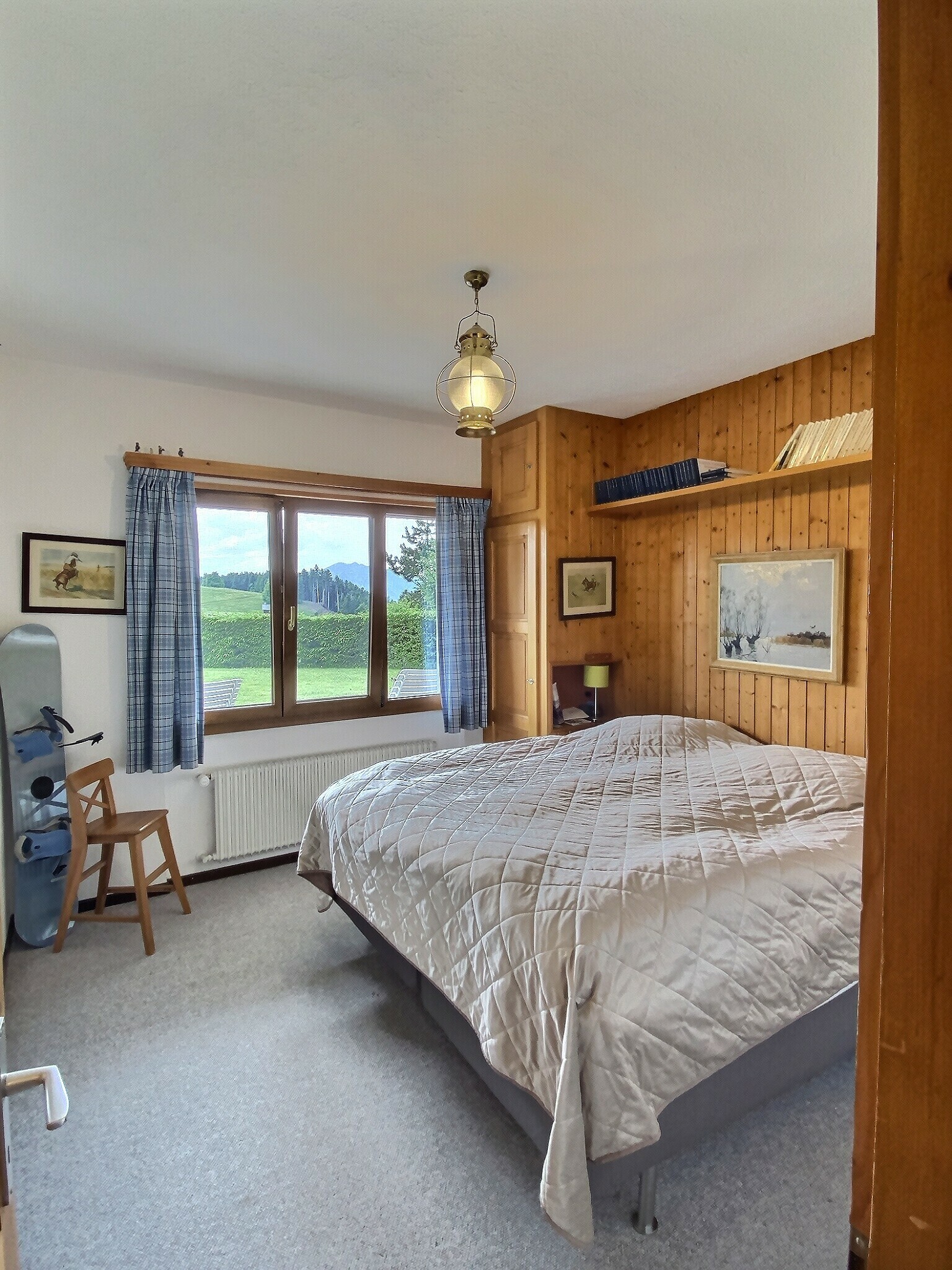 Gemütliches Schlafzimmer mit Holzvertäfelung und Bergblick