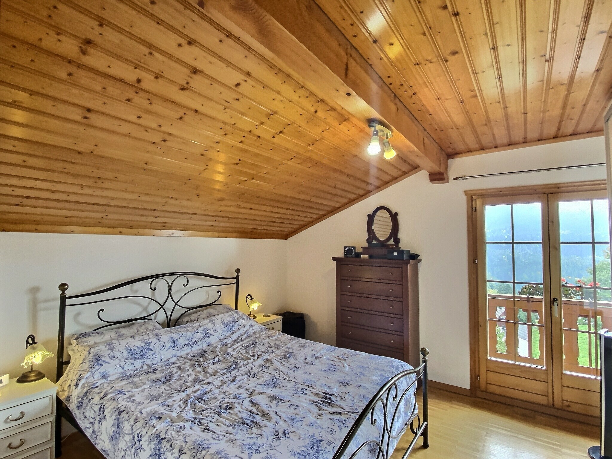 Gemütliches Schlafzimmer mit Holzdecke und Balkonblick
