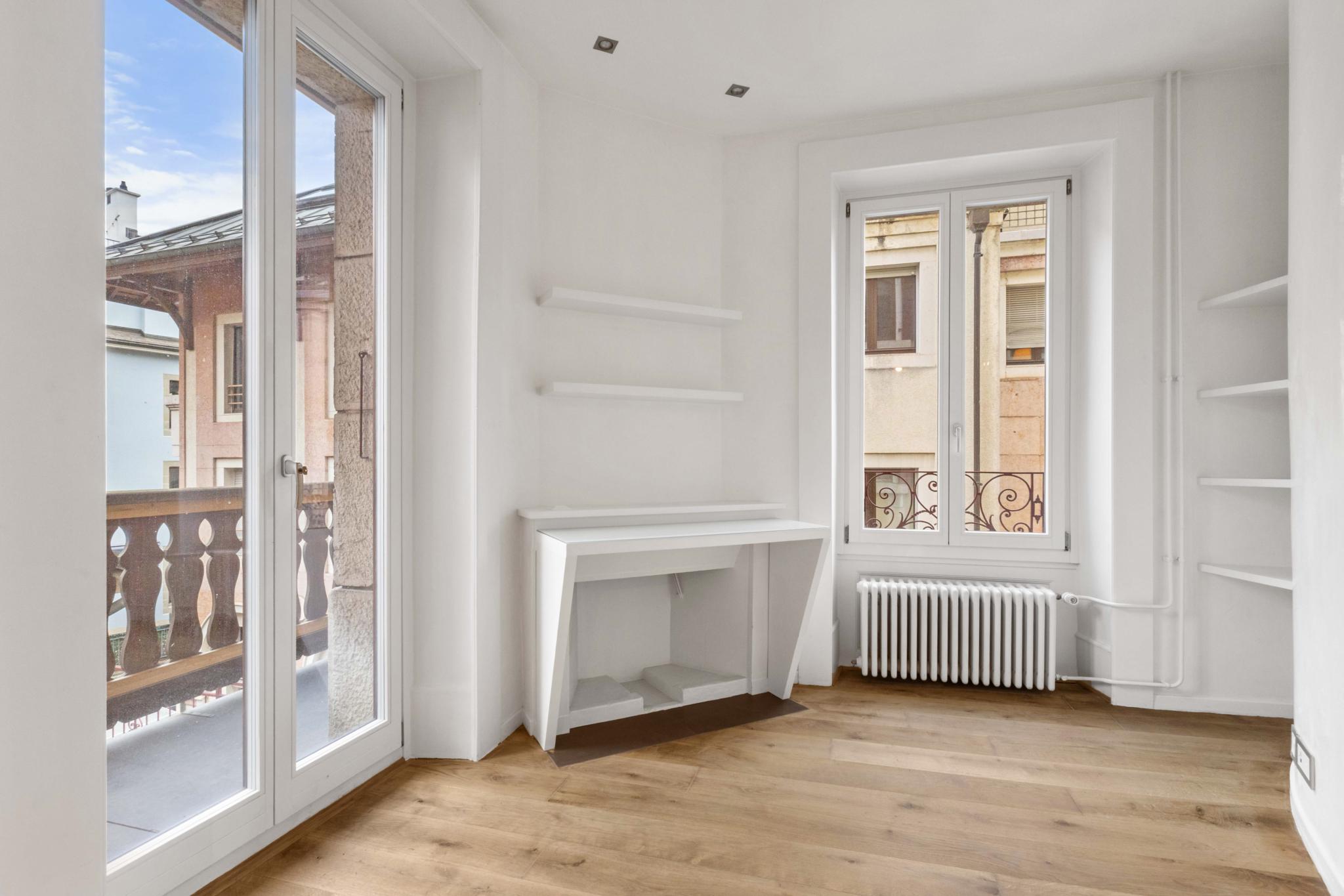 Heller kleiner Raum mit Balkon und weißen Einbauten