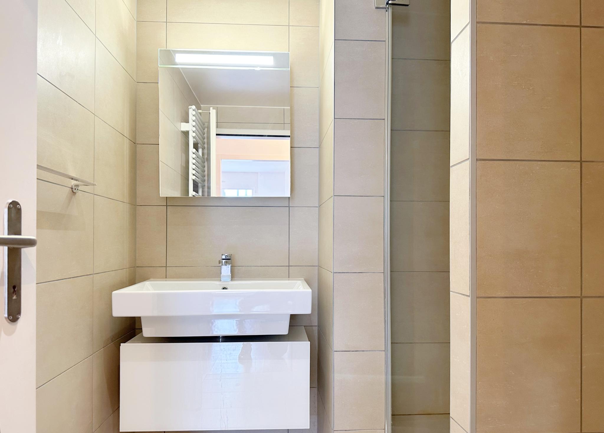 Kleines Badezimmer mit Waschbecken und Spiegel