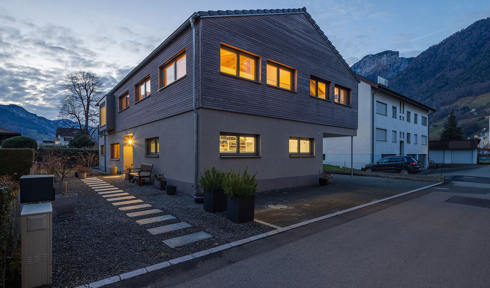 Modernes Haus mit Bergkulisse bei Dämmerung