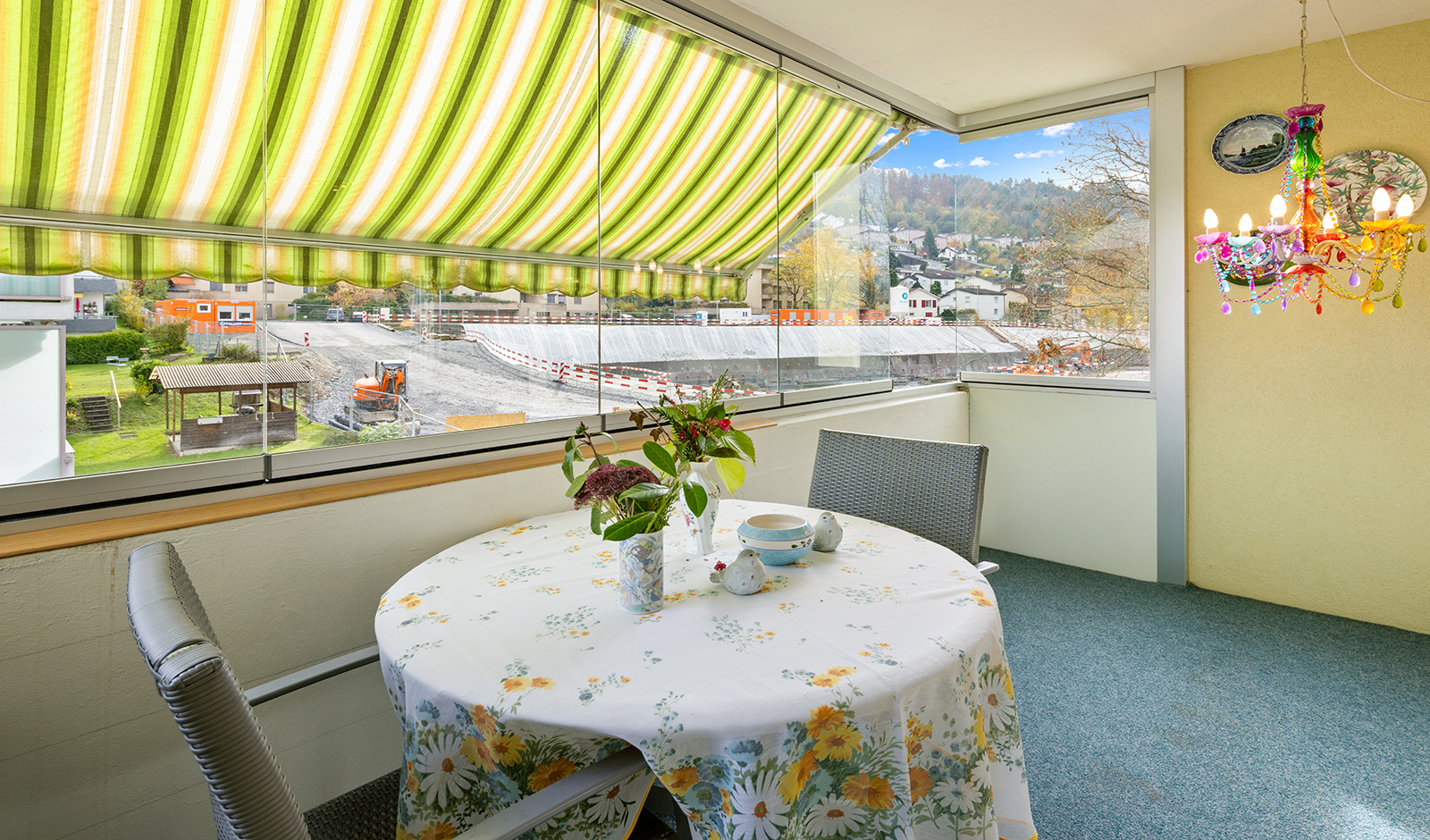 Überdachter Balkon mit Blick ins Grüne und auf eine Baustelle
