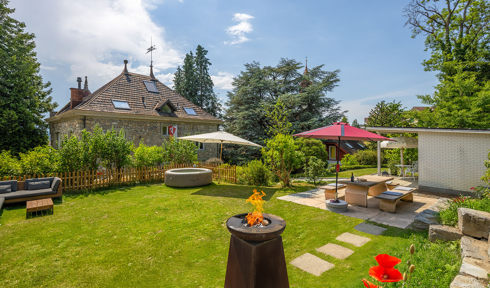 Großer Garten mit historischem Haus und Sitzbereichen