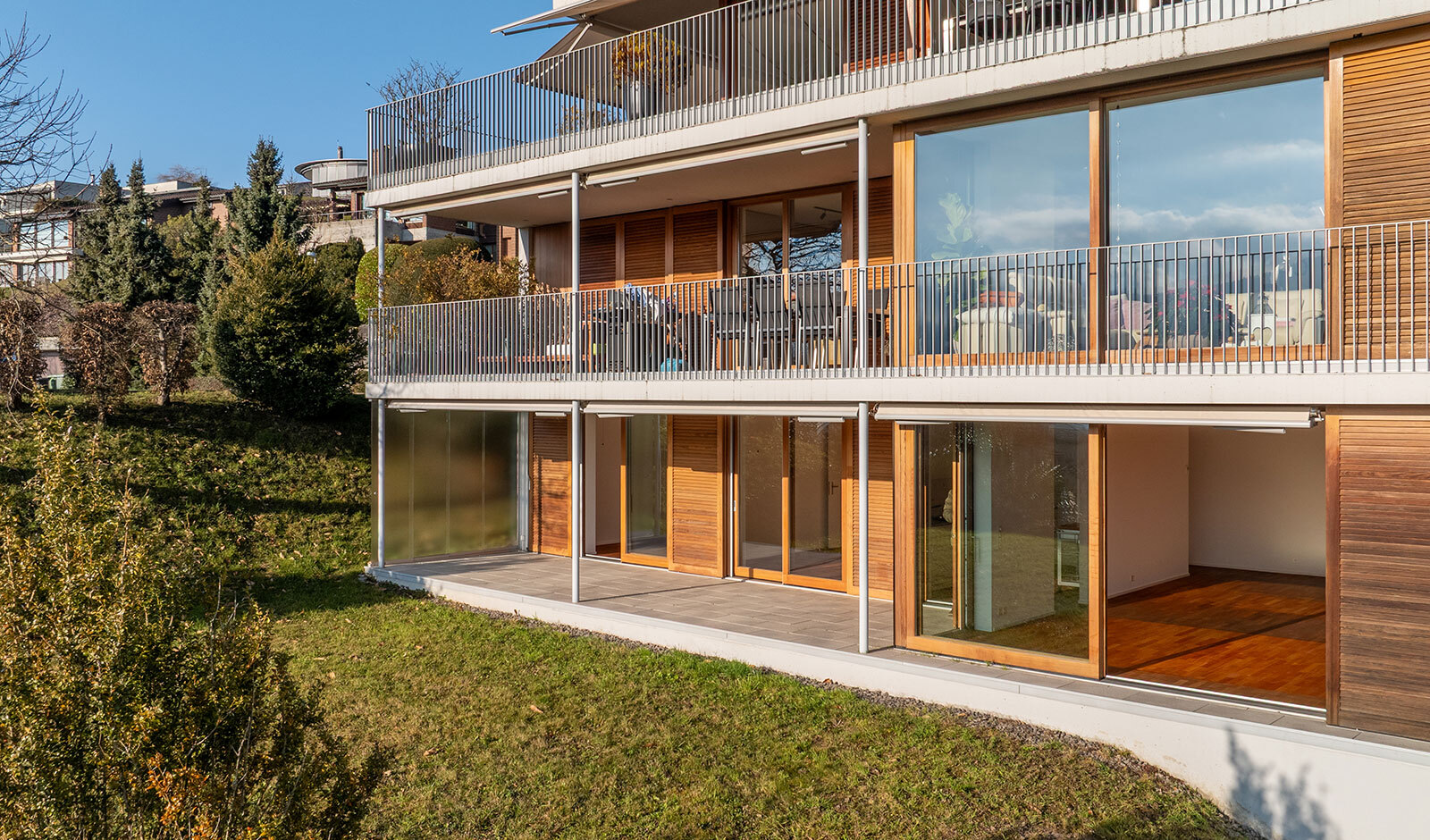 Mehrgeschossige moderne Wohnhausfassade mit Balkon und Garten