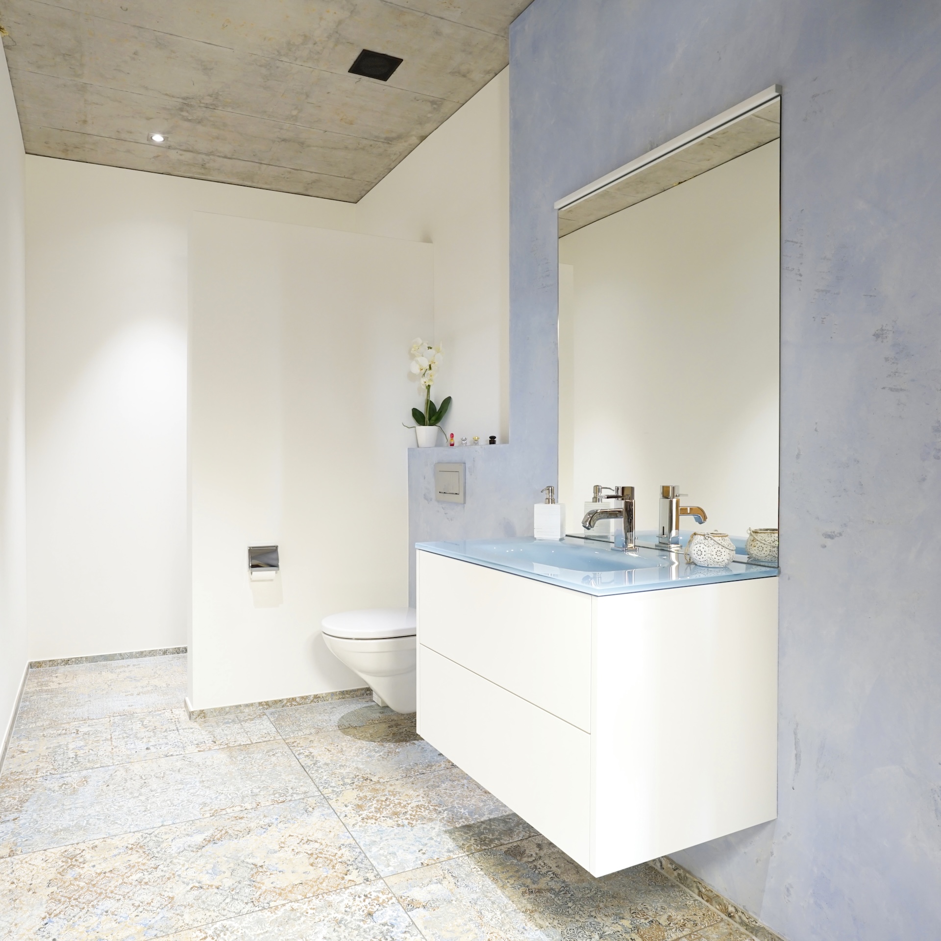 Modernes Badezimmer mit blauem Waschtisch und großem Spiegel