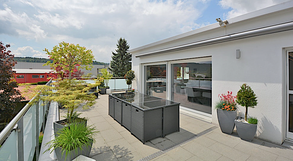 Moderne Dachterrasse mit Pflanzkübeln und Loungemöbeln
