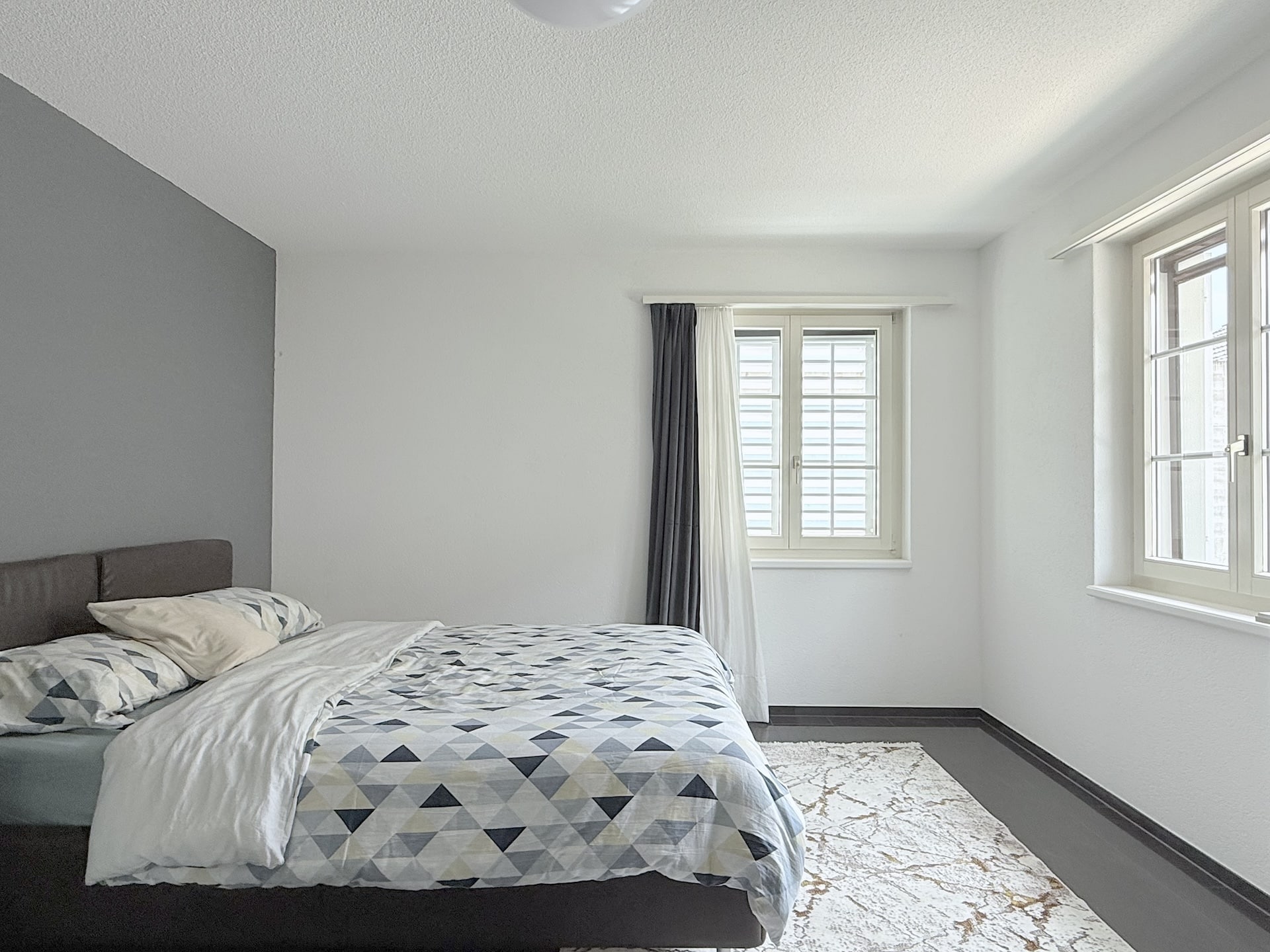 Helles Schlafzimmer mit Doppelbett und zwei Fenstern