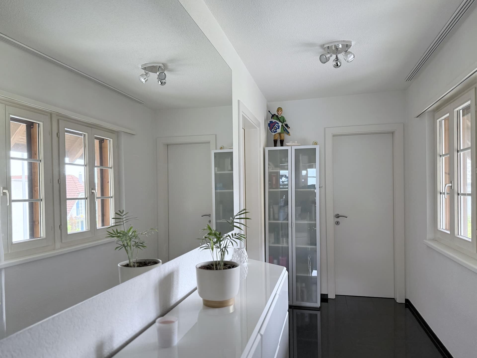 Heller Flur mit weißen Türen und Schrankvitrine