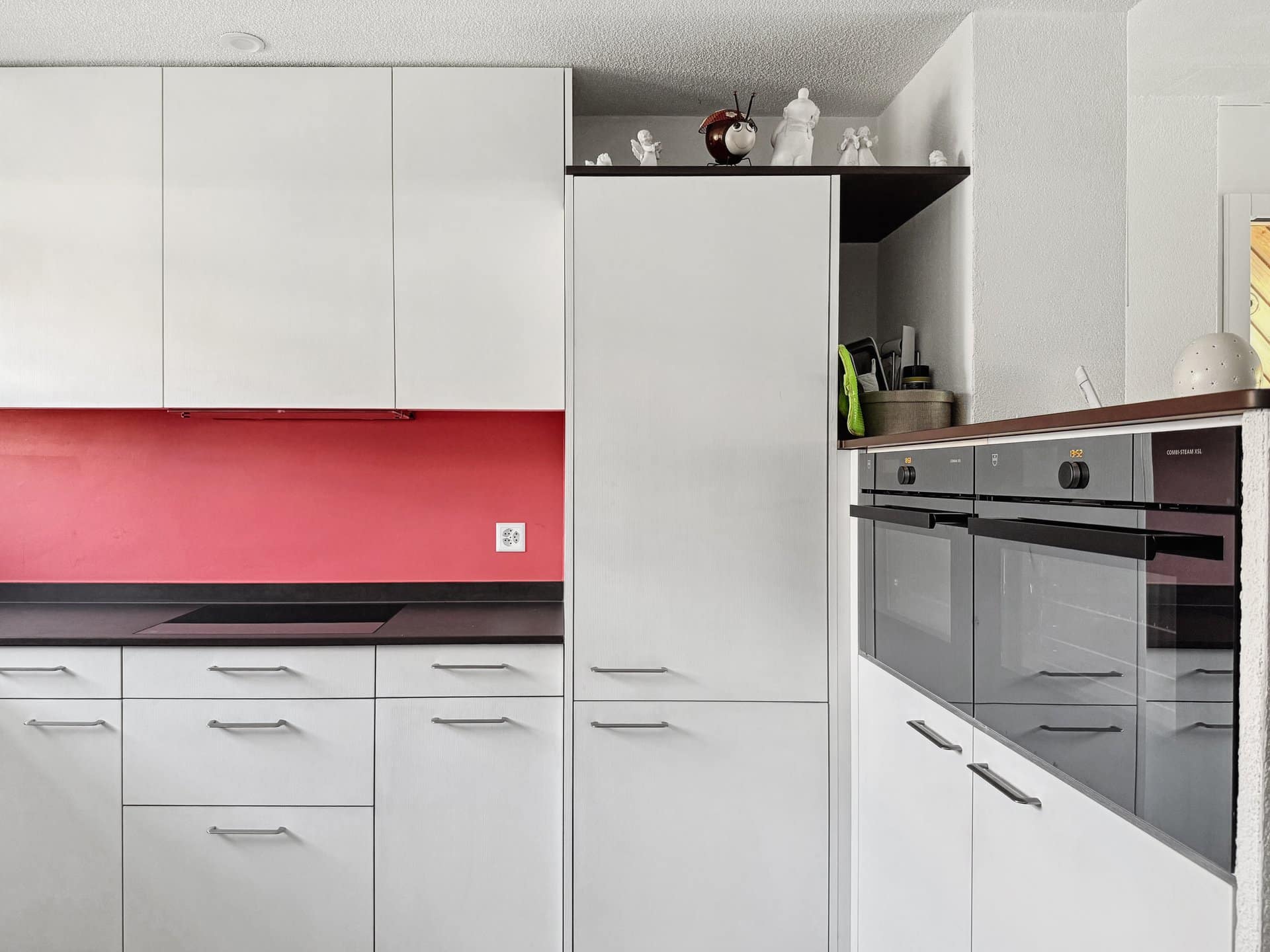 Moderne Einbauküche mit weißen Fronten und roter Nische