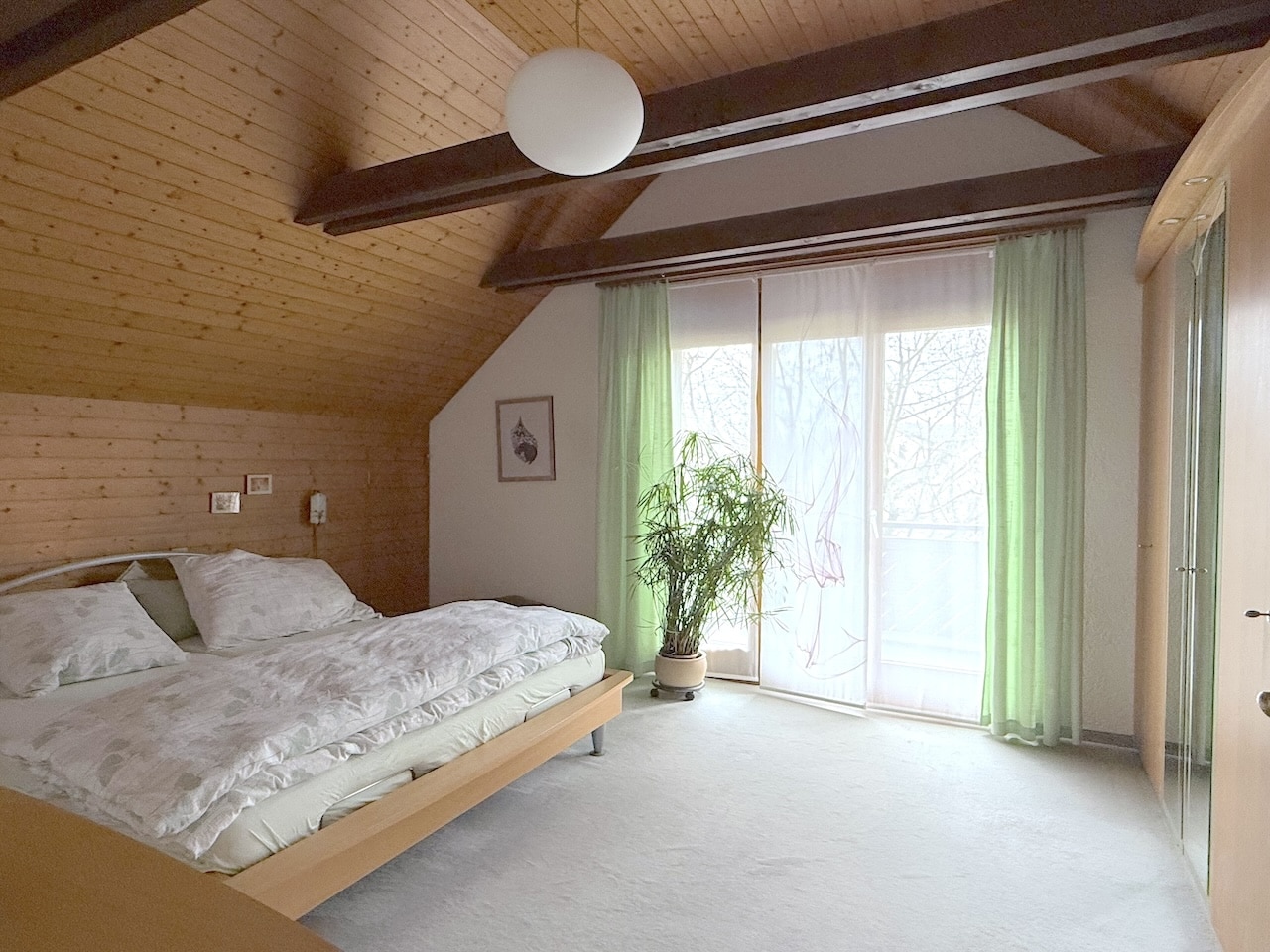 Helles Schlafzimmer mit Holzbalken und Balkonfenster