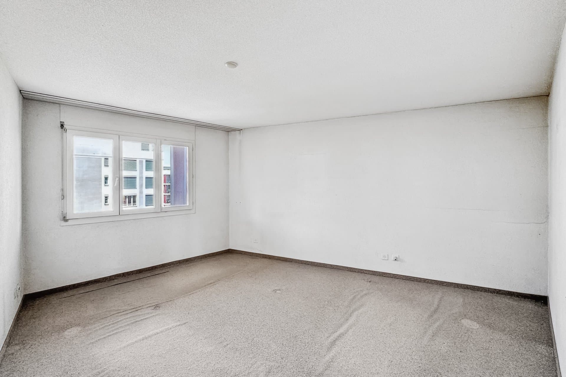 Leerer Raum mit Teppichboden und Fenster