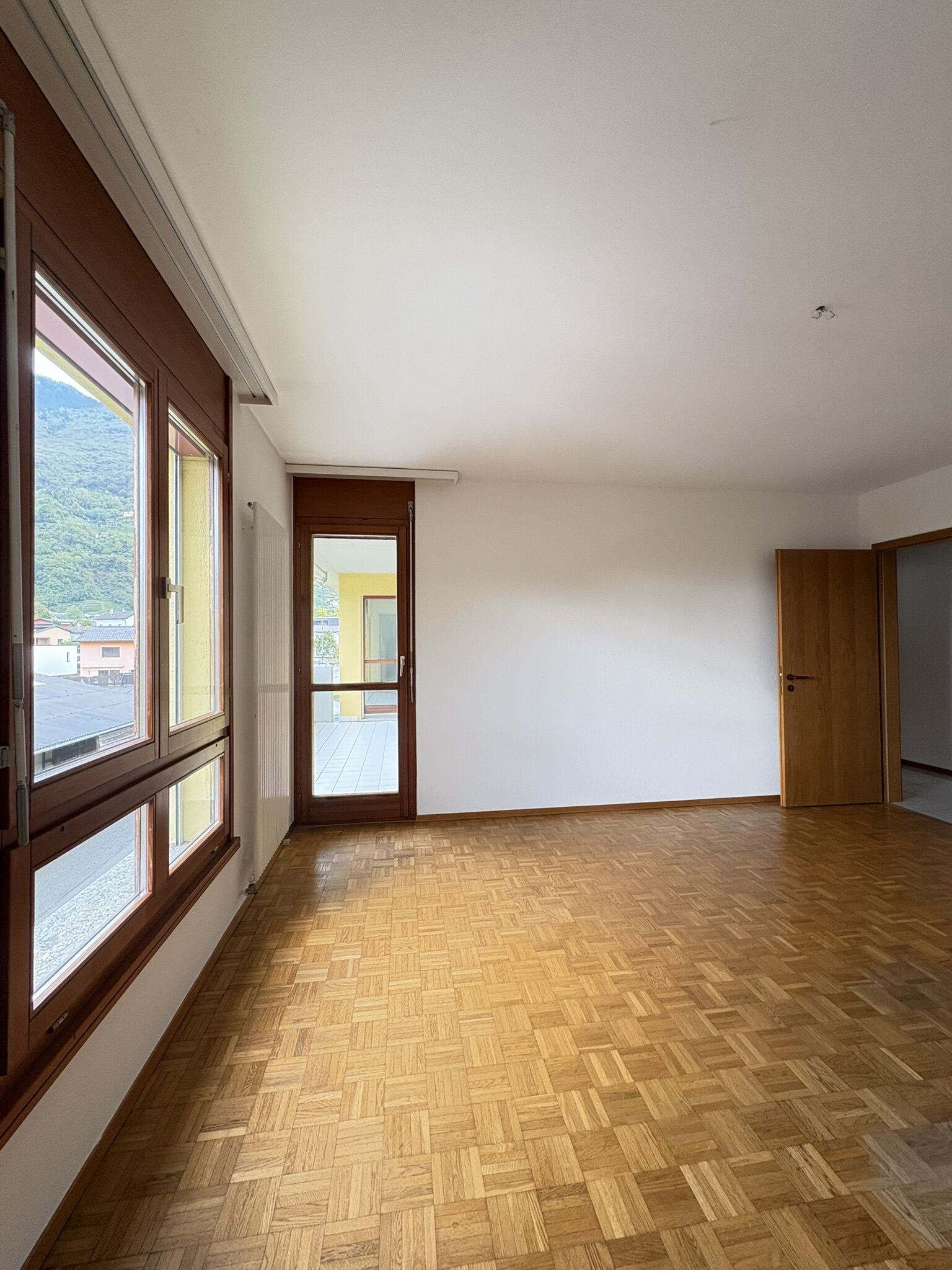 Leerer Wohnraum mit Parkett und großen Fenstern