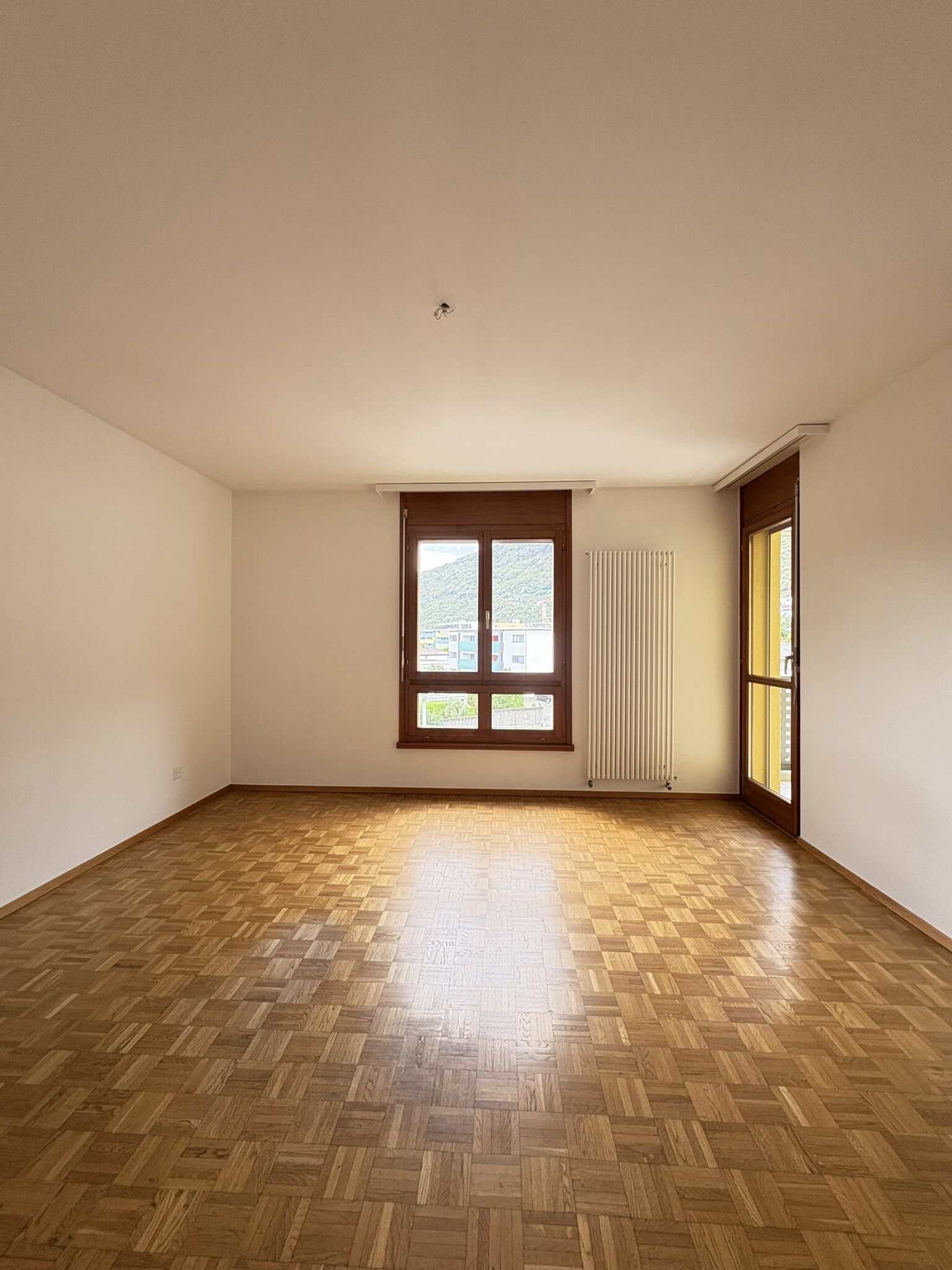 Leerer Wohnraum mit Parkett und Fenstern