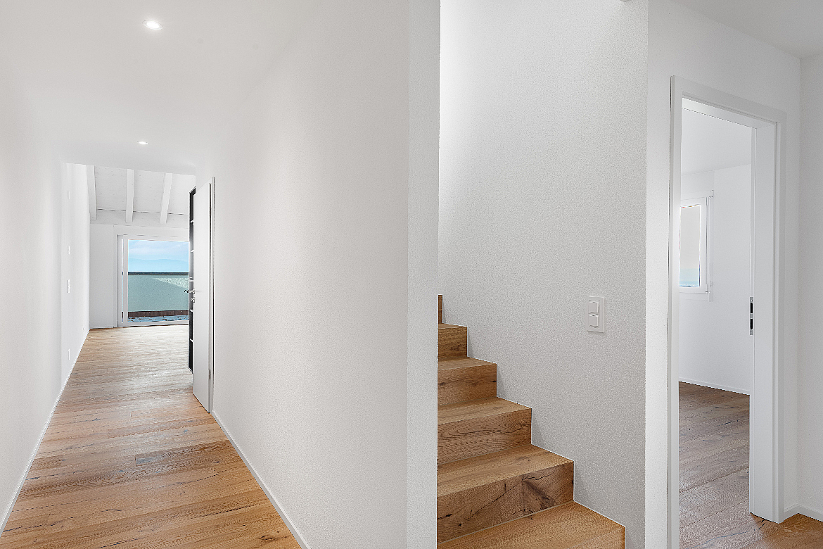 Heller Flur mit Holztreppe und Meerblick