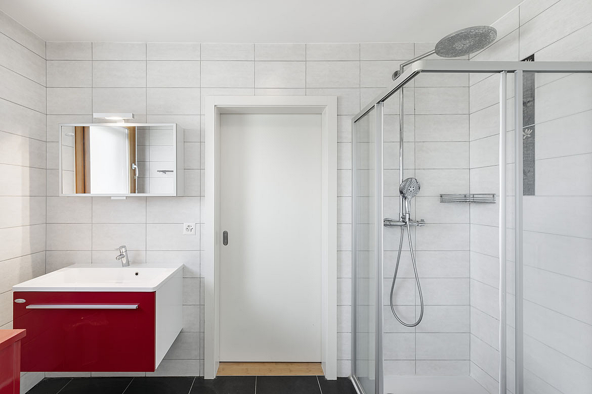 Modernes Badezimmer mit Dusche und rotem Waschtischunterschrank