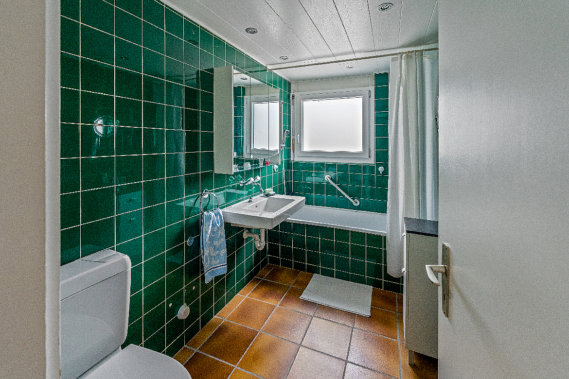 Badezimmer mit grünen Fliesen und Badewanne