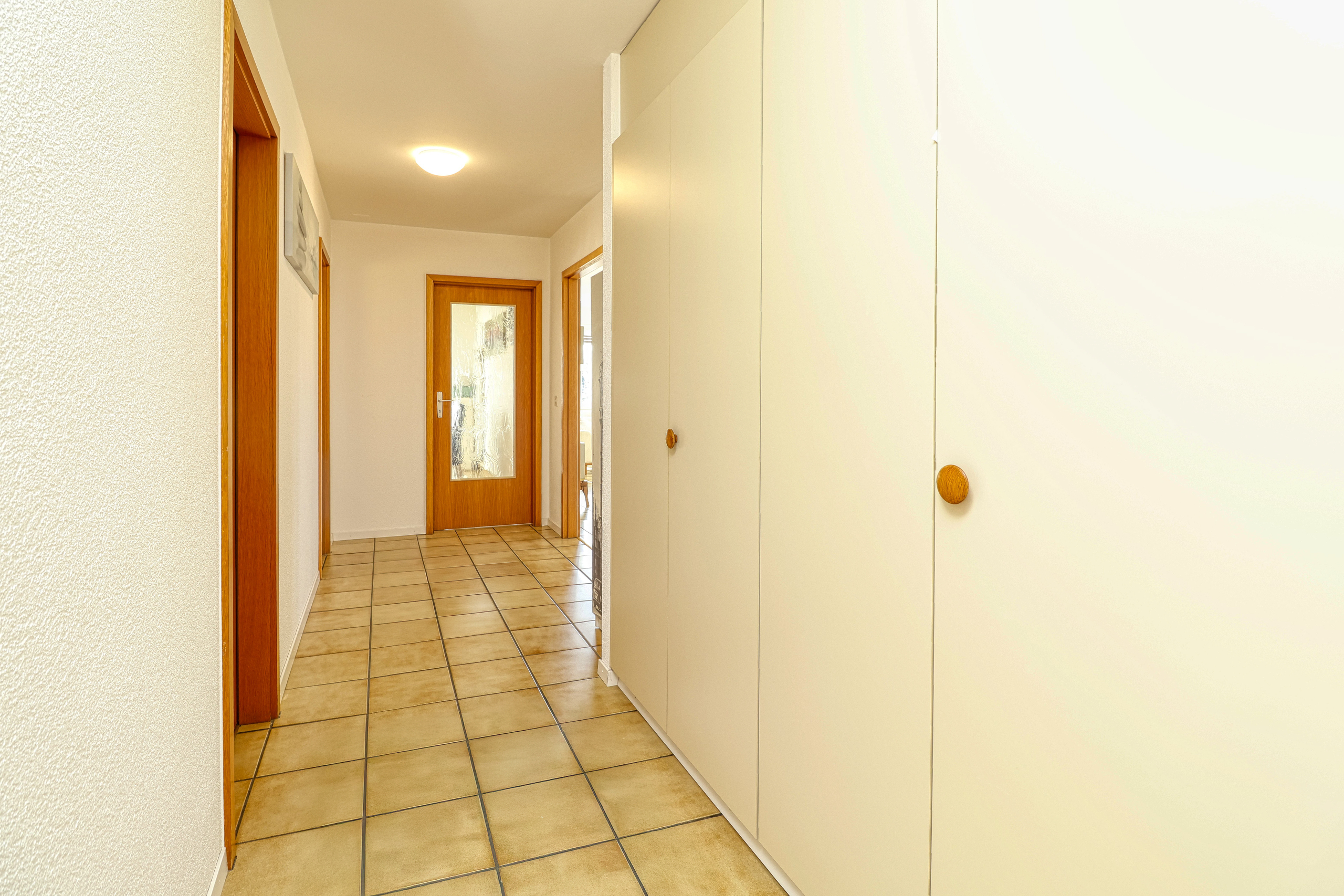 Heller Flur mit Fliesenboden und Einbauschrank