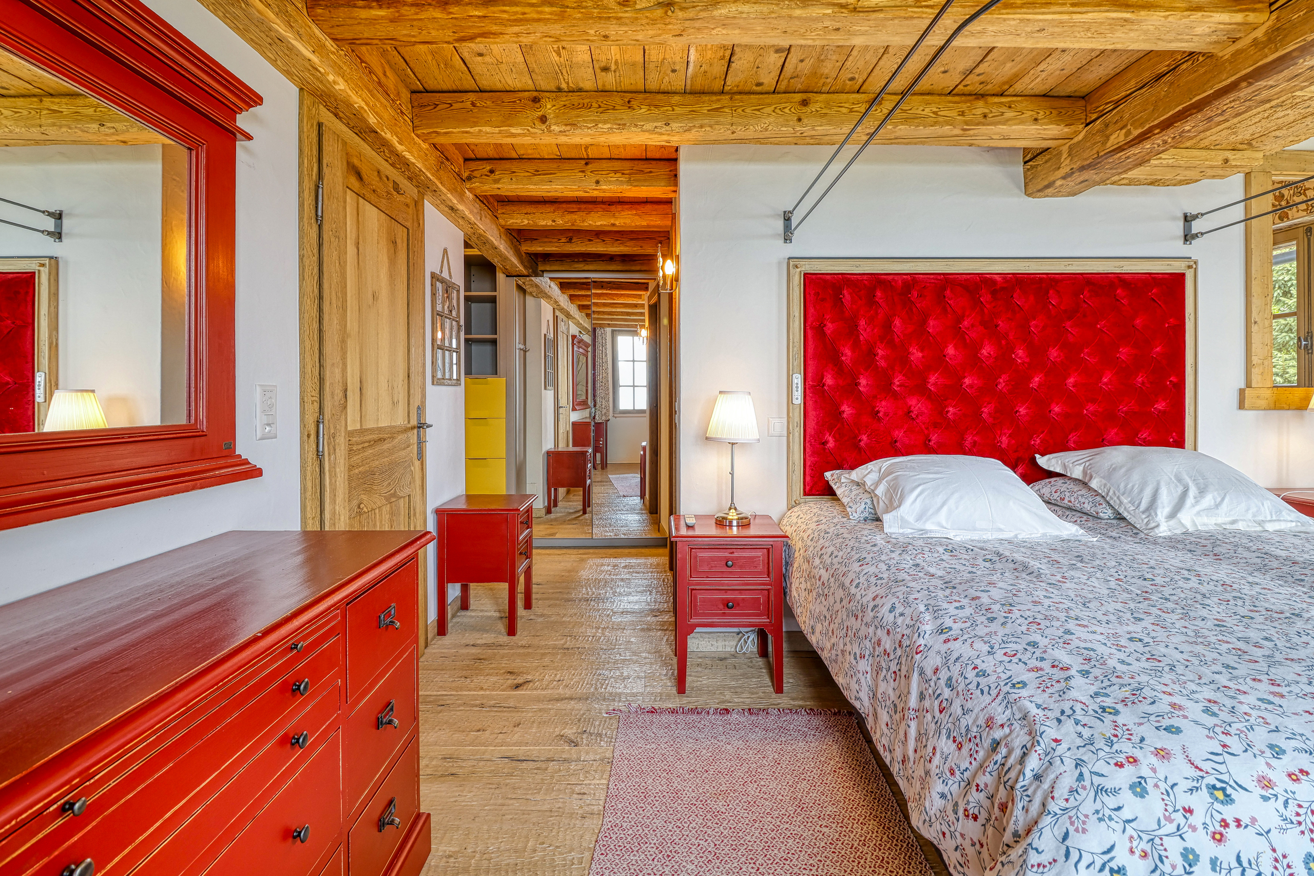 Gemütliches Schlafzimmer mit rustikalen Holzbalken und kräftigen roten Akzenten