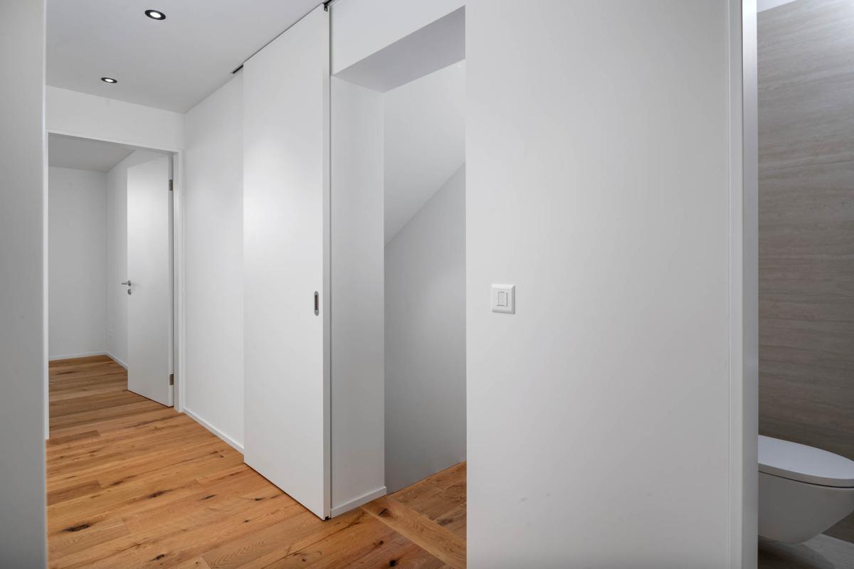 Heller Flur mit Schiebetür und sichtbarer Treppe