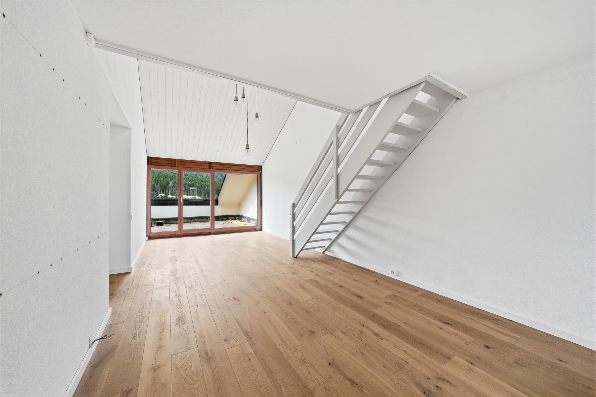 Heller leerer Wohnraum mit Treppe zur Galerie