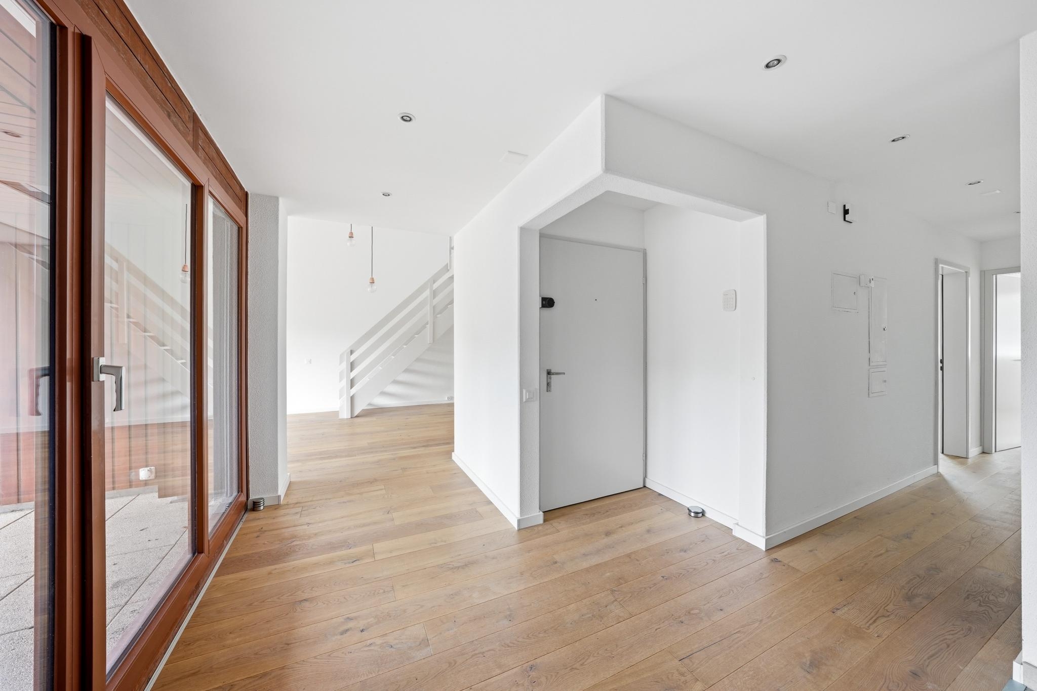 Heller Flur mit Holzparkett und Glasfront