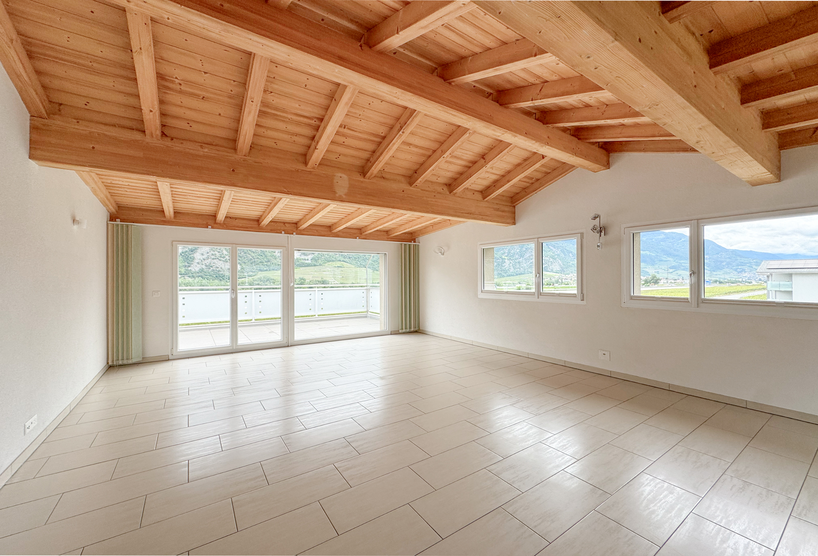 Heller leerer Wohnraum mit Holzdecke und Bergblick