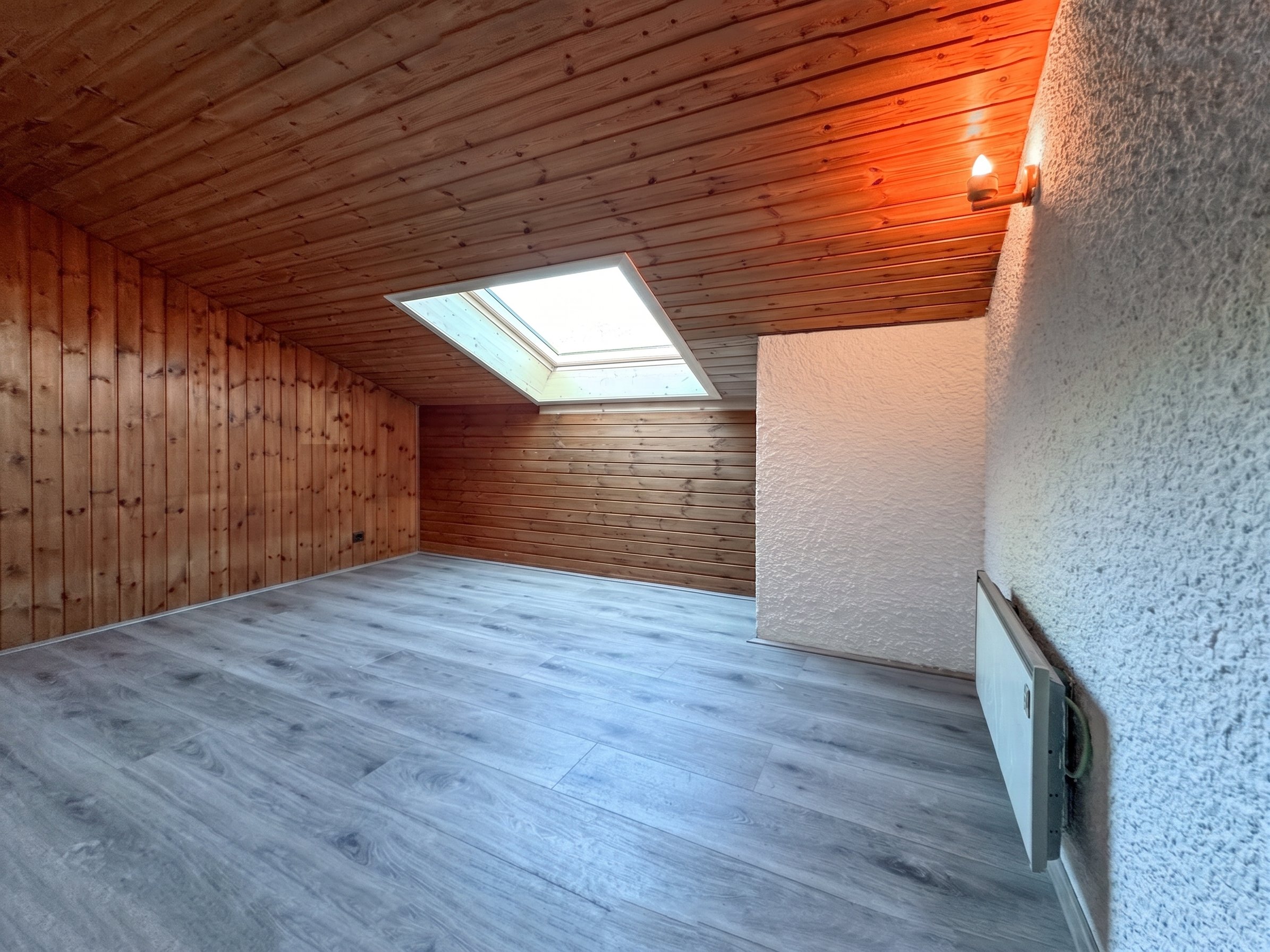 Leerer Dachraum mit Holzverkleidung und Dachfenster