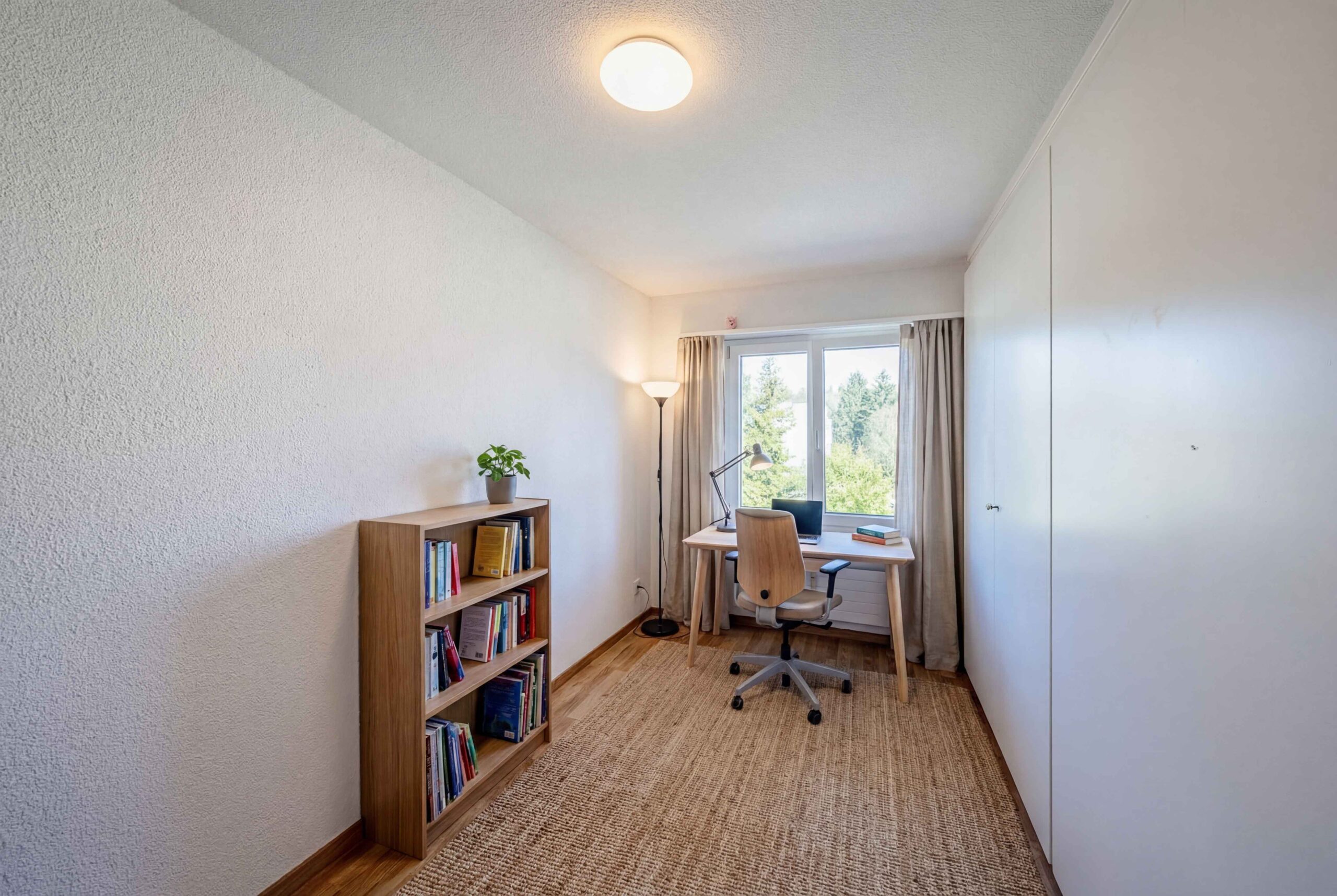 Helles Arbeitszimmer mit Schreibtisch und Regal