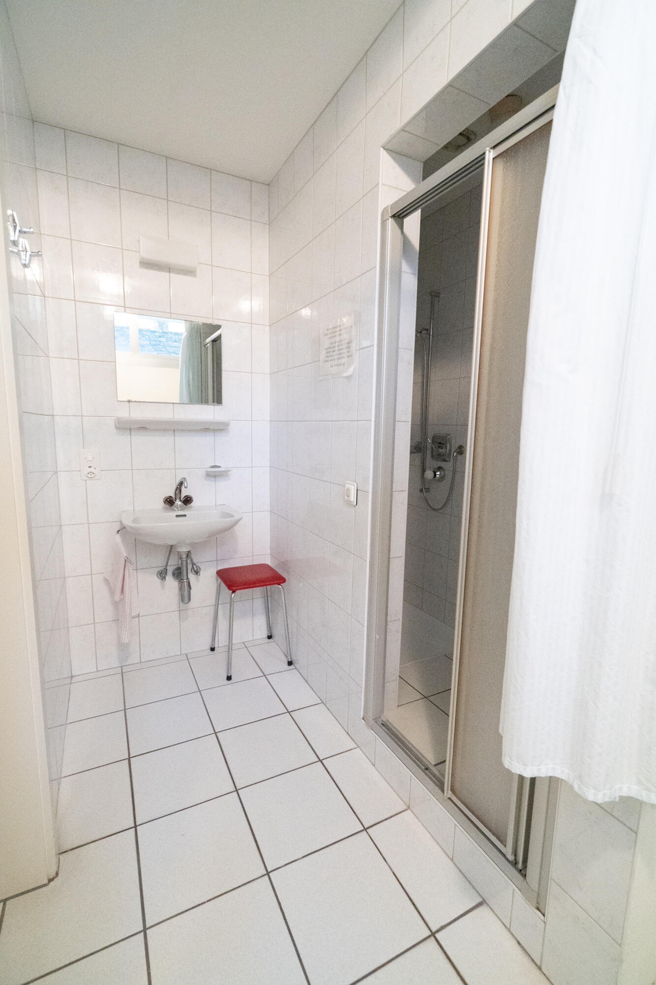 Kleines gefliestes Badezimmer mit Dusche und Waschbecken