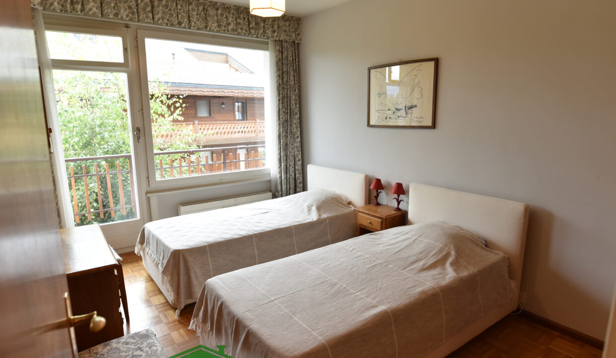 Schlafzimmer mit zwei Betten und Balkonblick