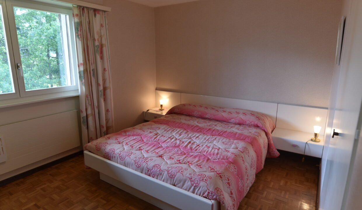 Schlafzimmer mit Doppelbett und Fensterblick ins Grüne